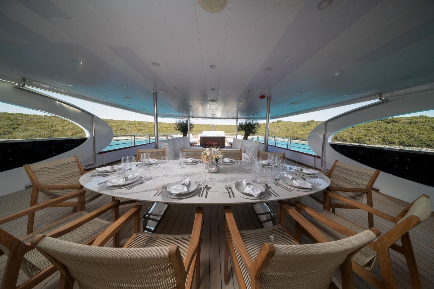 luxury yacht covered dining area with circular table set for eight guests