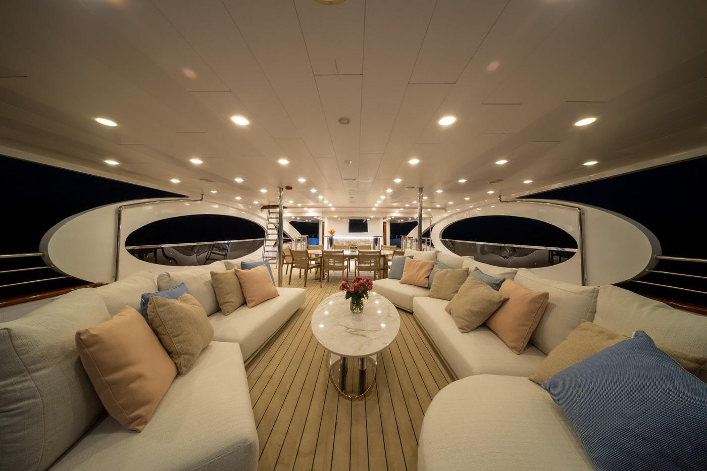 luxury yacht main deck salon with curved white seating and teak flooring