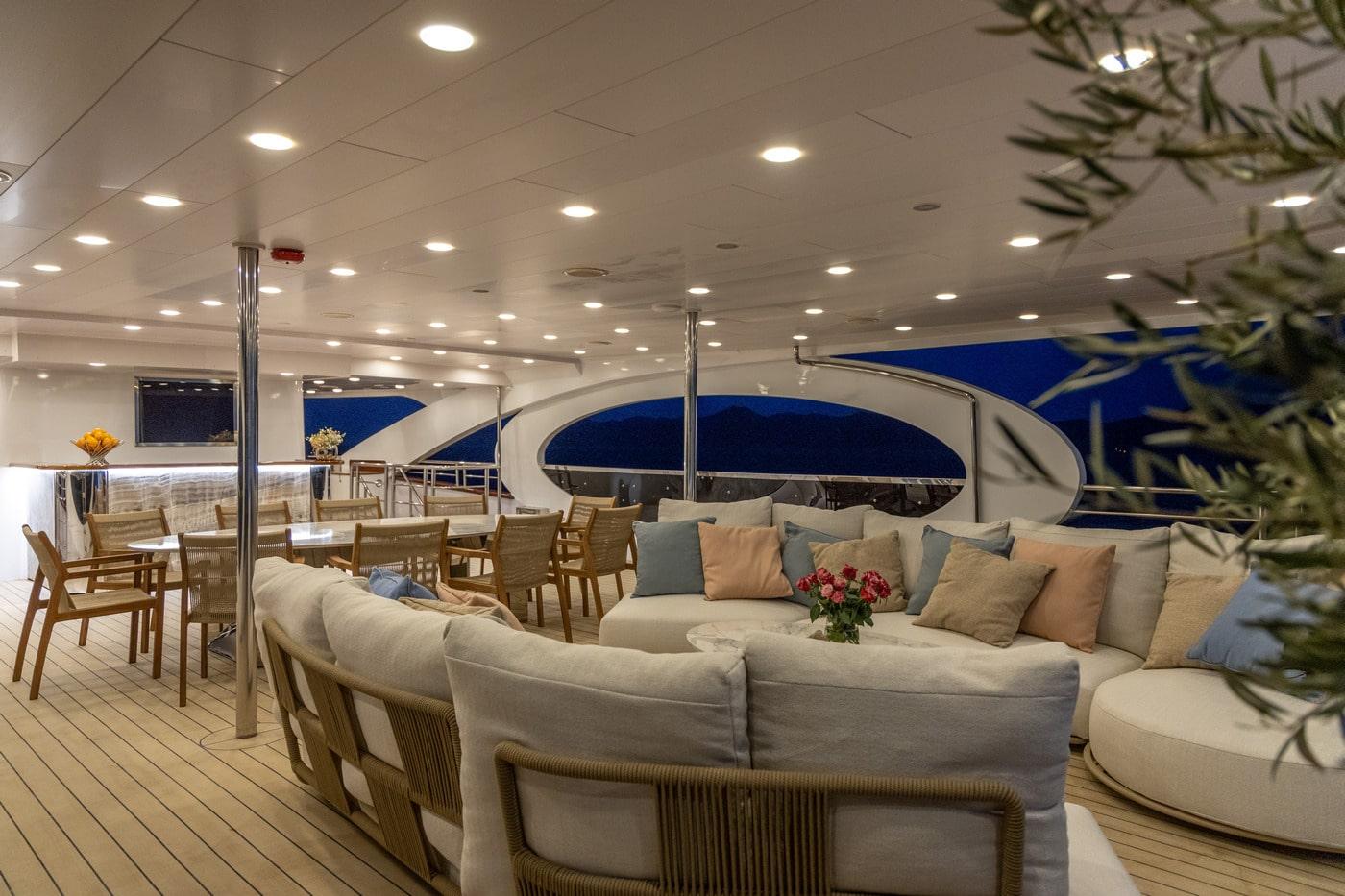 luxury yacht interior salon with sectional sofa and dining chairs at night