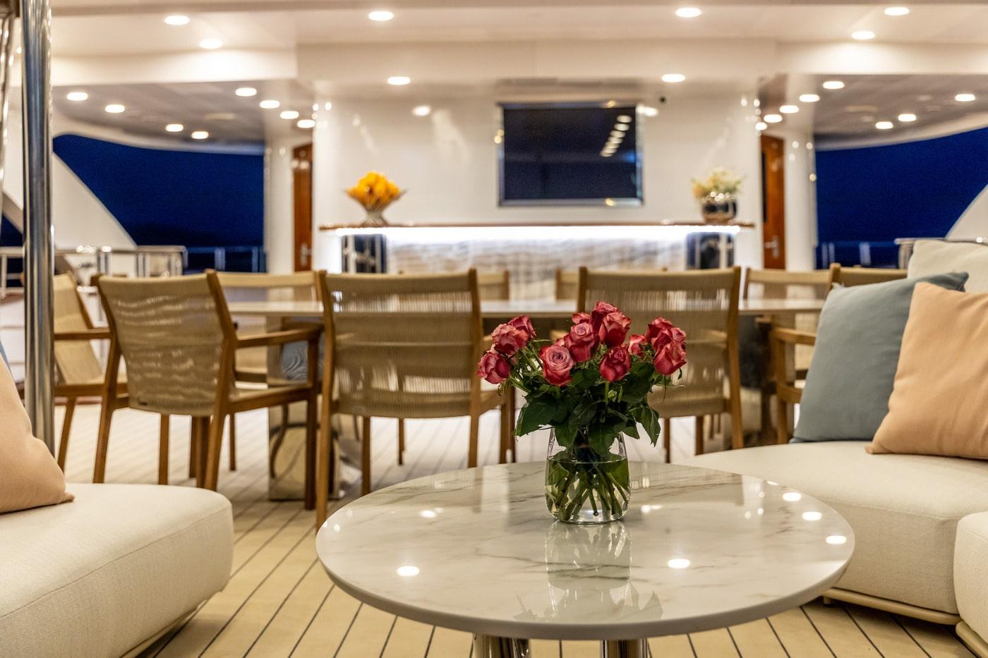 luxury yacht interior salon with coffee table roses and dining area