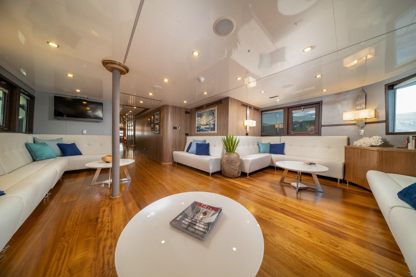 Elegant yacht main salon with white seating, teak floors, modern lighting