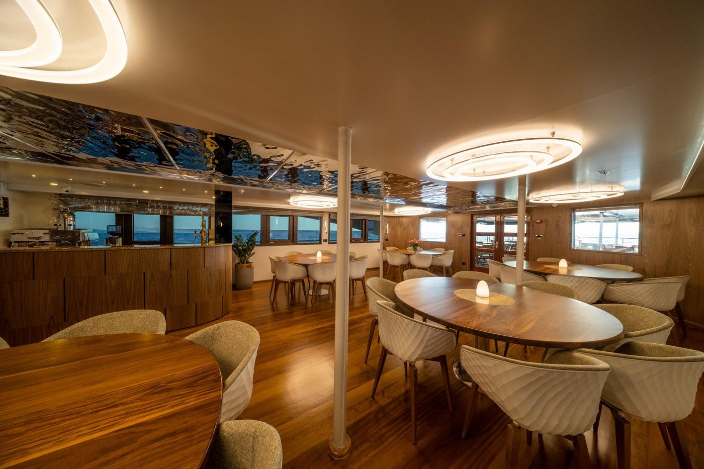 elegant yacht main salon with teak floors multiple dining tables cream chairs