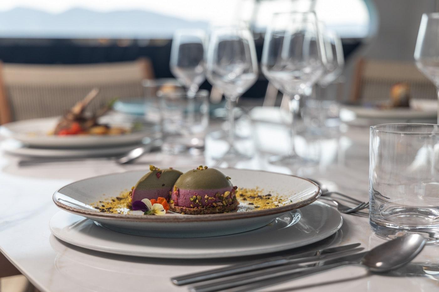 Fine dining dessert presentation with wine glasses aboard luxury yacht