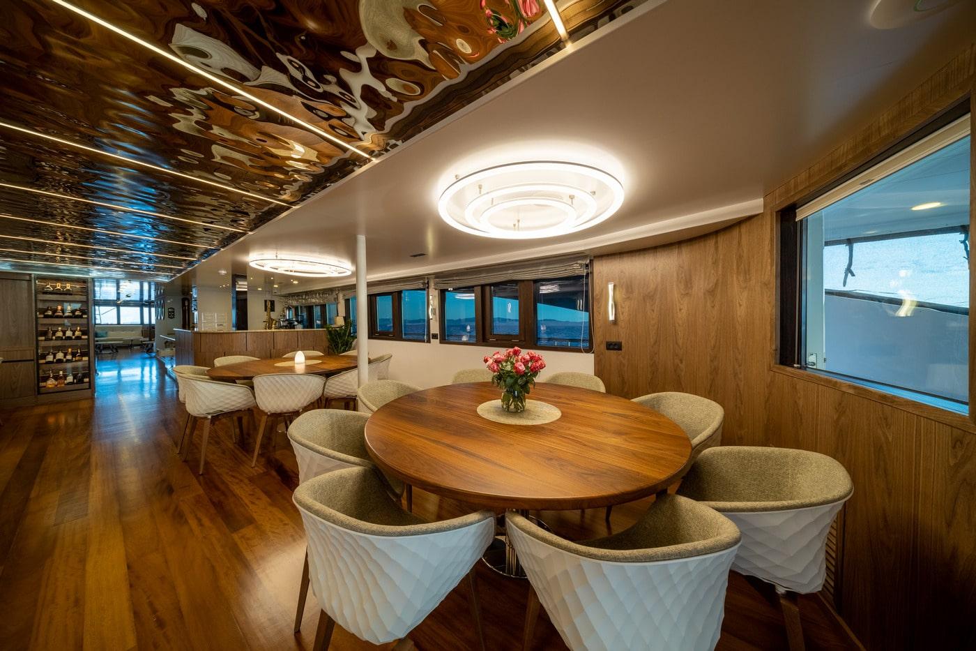 luxury yacht main salon with round dining table and mirrored ceiling