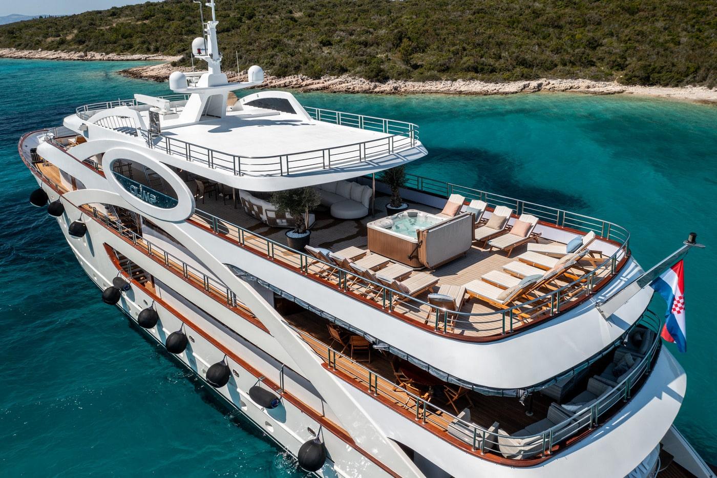 White luxury motor yacht with sun deck and jacuzzi anchored in crystal clear turquoise waters