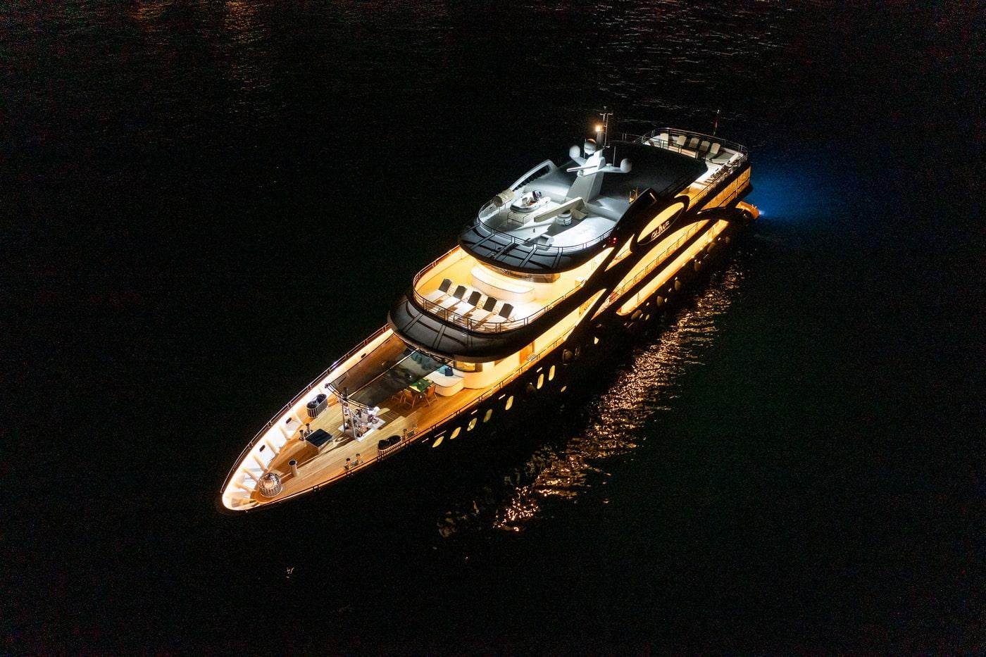 Aerial night view of illuminated luxury motor yacht on dark water