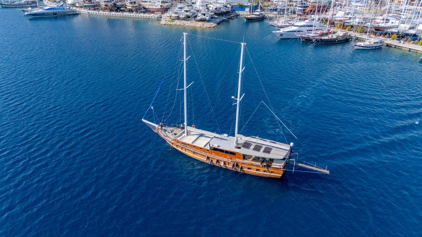 aerial view of traditional wooden gulet yacht anchored in deep blue Mediterranean waters near coastal marina