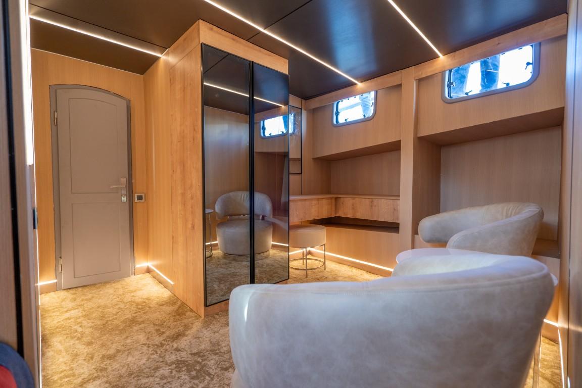 yacht guest cabin featuring twin beds with white linens and built-in mirrored wardrobe