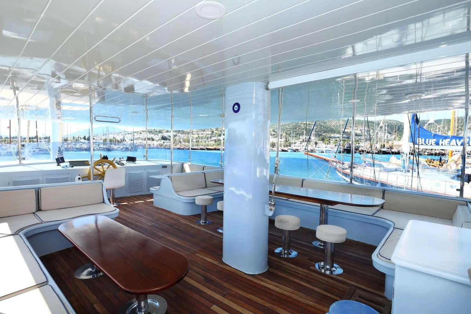 yacht covered deck lounge with white seating, bar stools, and panoramic marina views