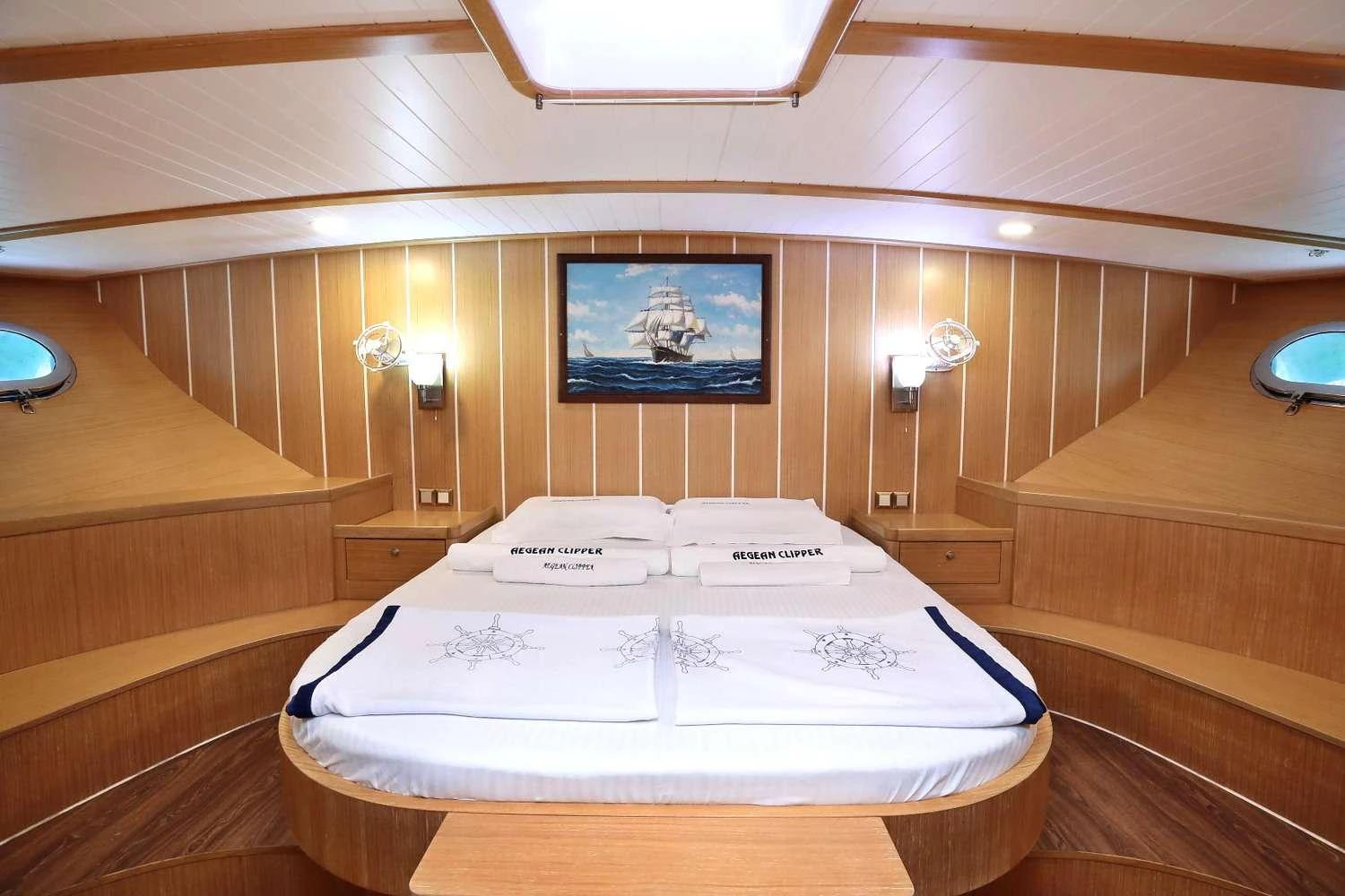 yacht cabin interior featuring double bed with white linens, nautical painting, and wooden paneling