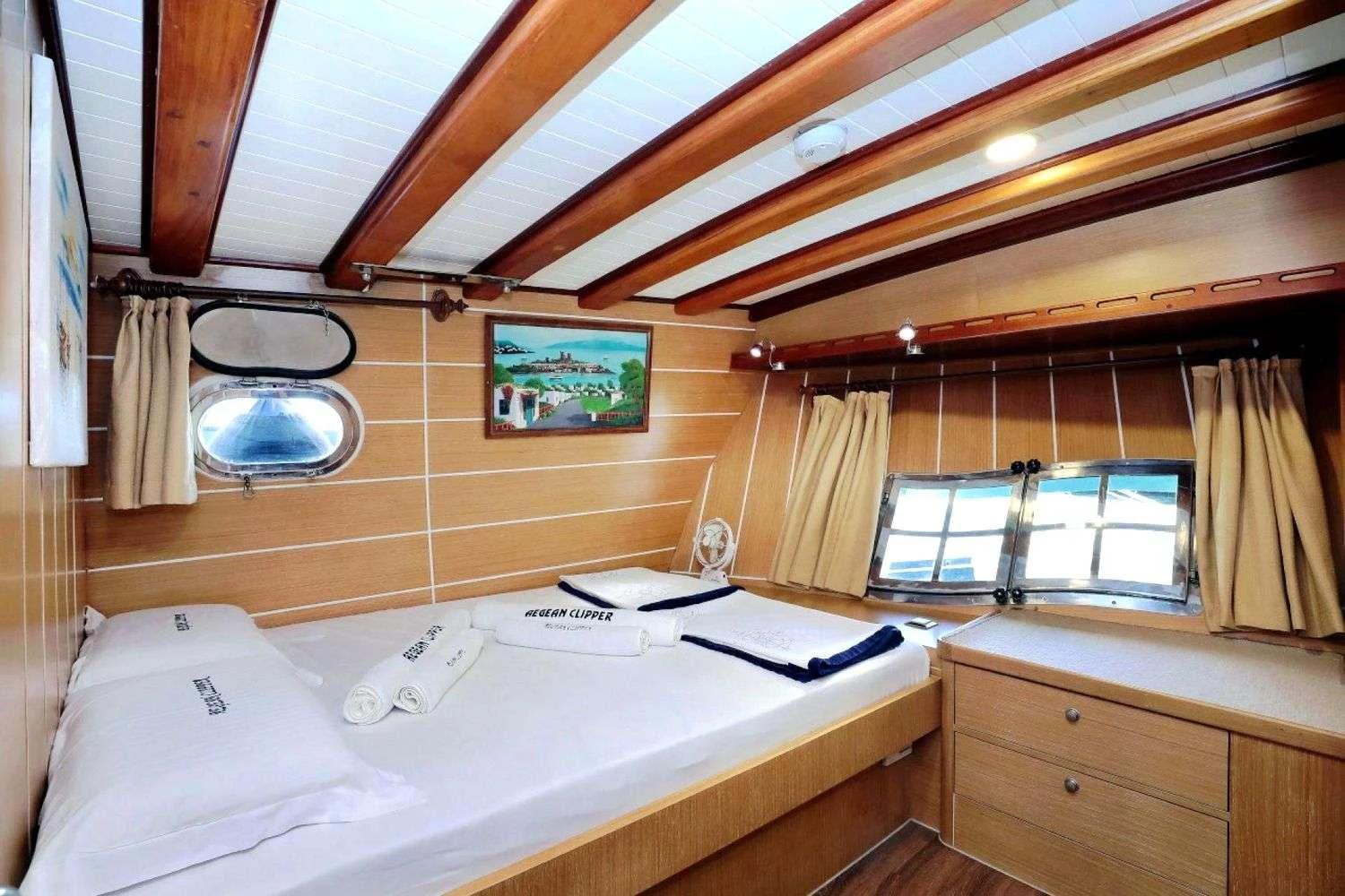 yacht guest cabin featuring double bed with white linens and wooden interior paneling