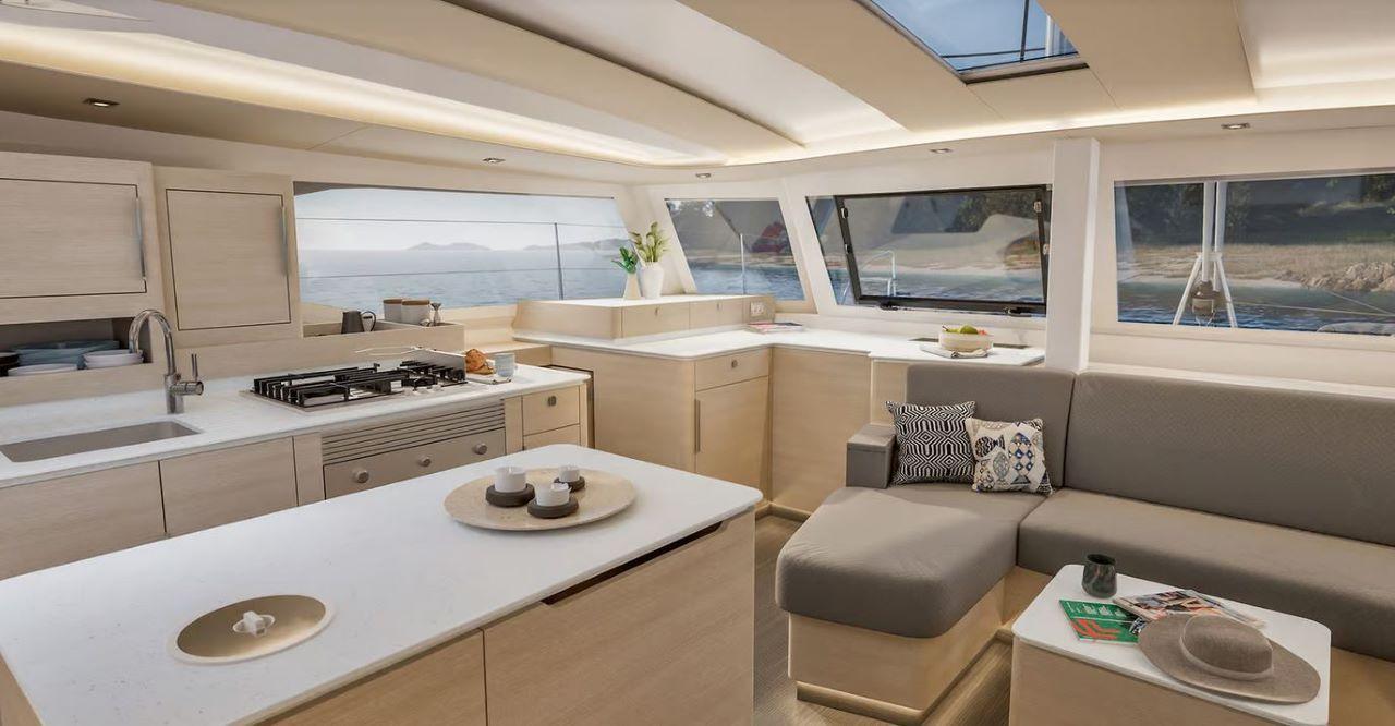 Luxury catamaran saloon with galley kitchen, central island, L-shaped sofa, and panoramic sea views