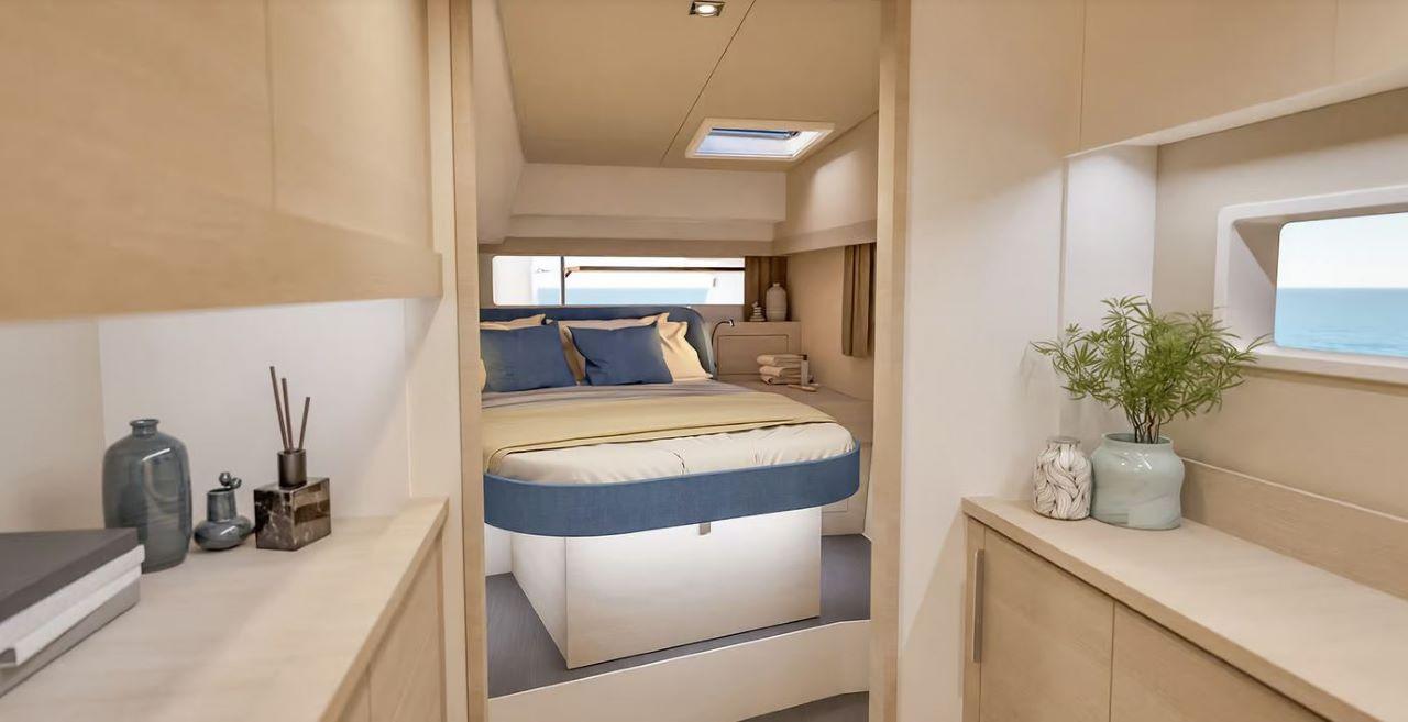 yacht double cabin with blue and cream bedding, overhead skylight hatch, and ocean view window