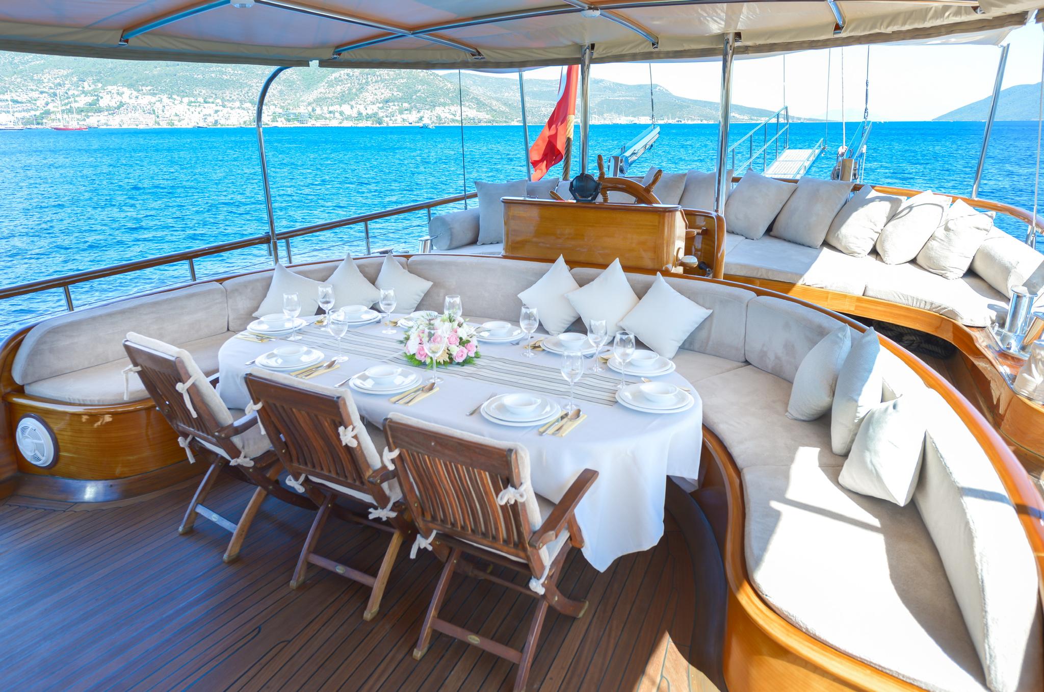 gulet aft deck with formal dining table, teak chairs, and curved seating banquette