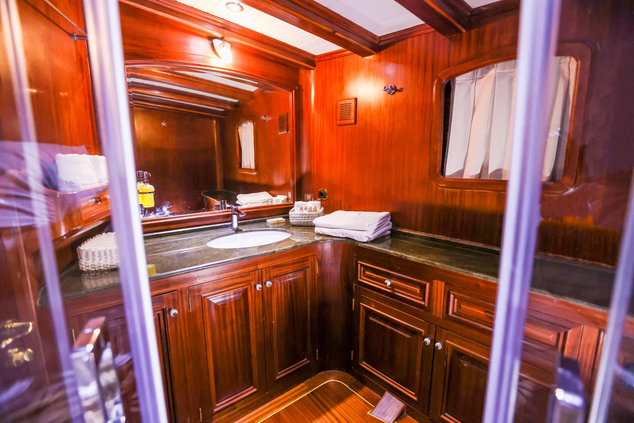 yacht bathroom featuring rich wood paneling, vanity with sink, mirror and towels