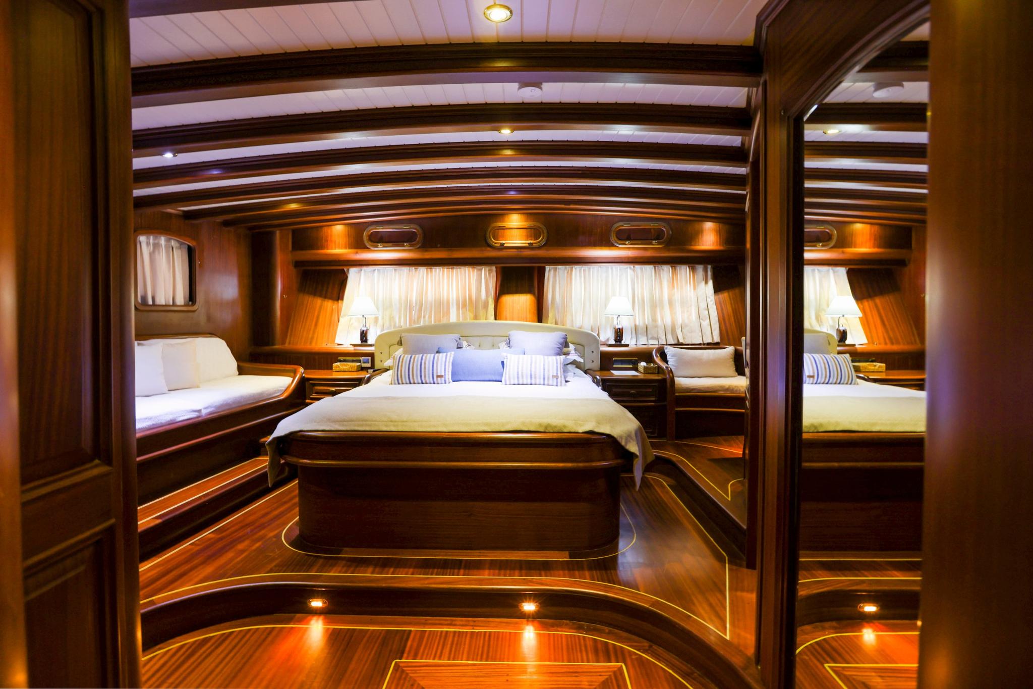 yacht guest cabin featuring central double bed with striped pillows and twin side berths