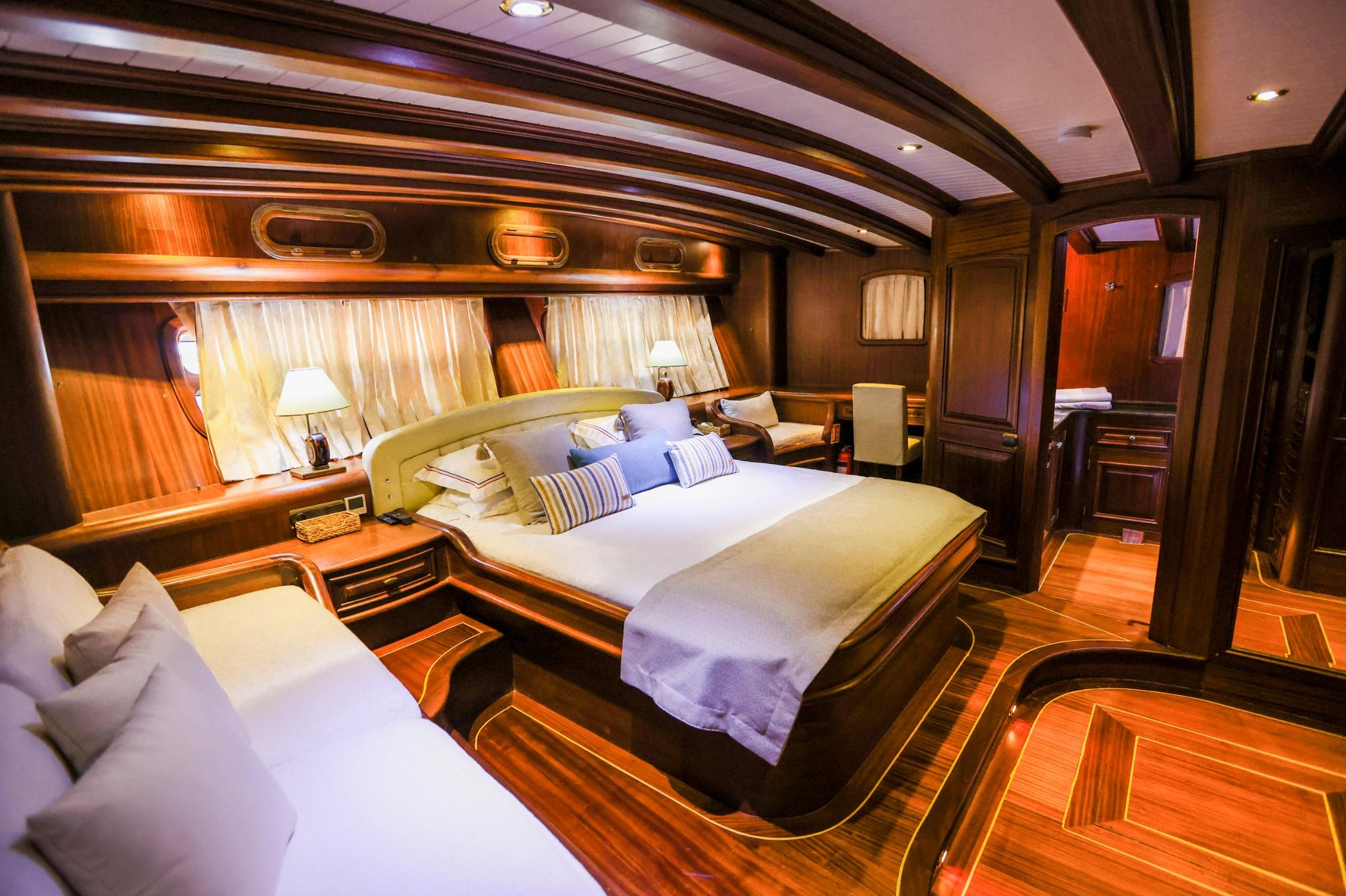 yacht master cabin with king bed white linens wood paneling curved ceiling beams