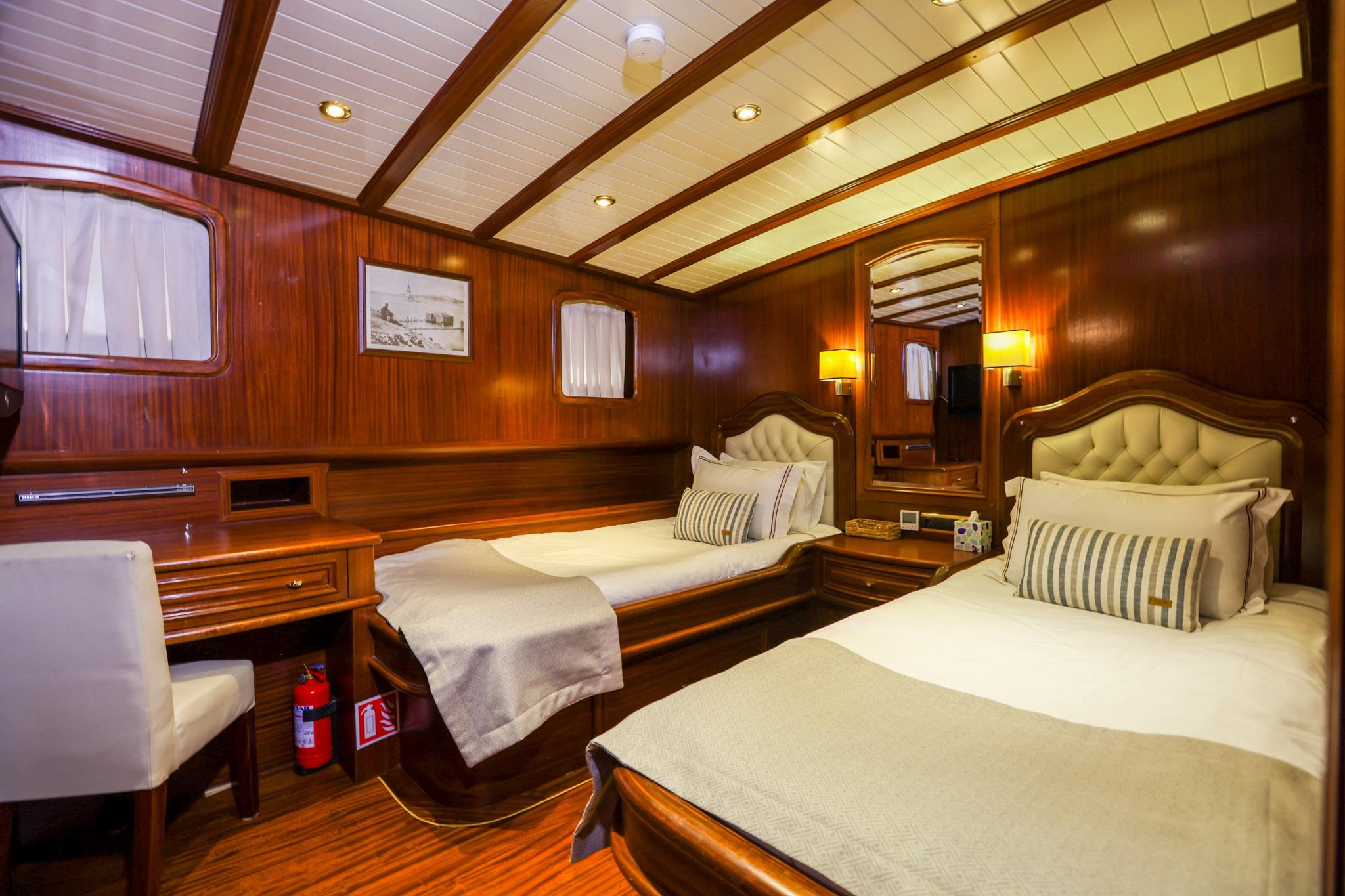 Yacht twin cabin with two single beds, cream upholstered headboards, and rich wood paneling