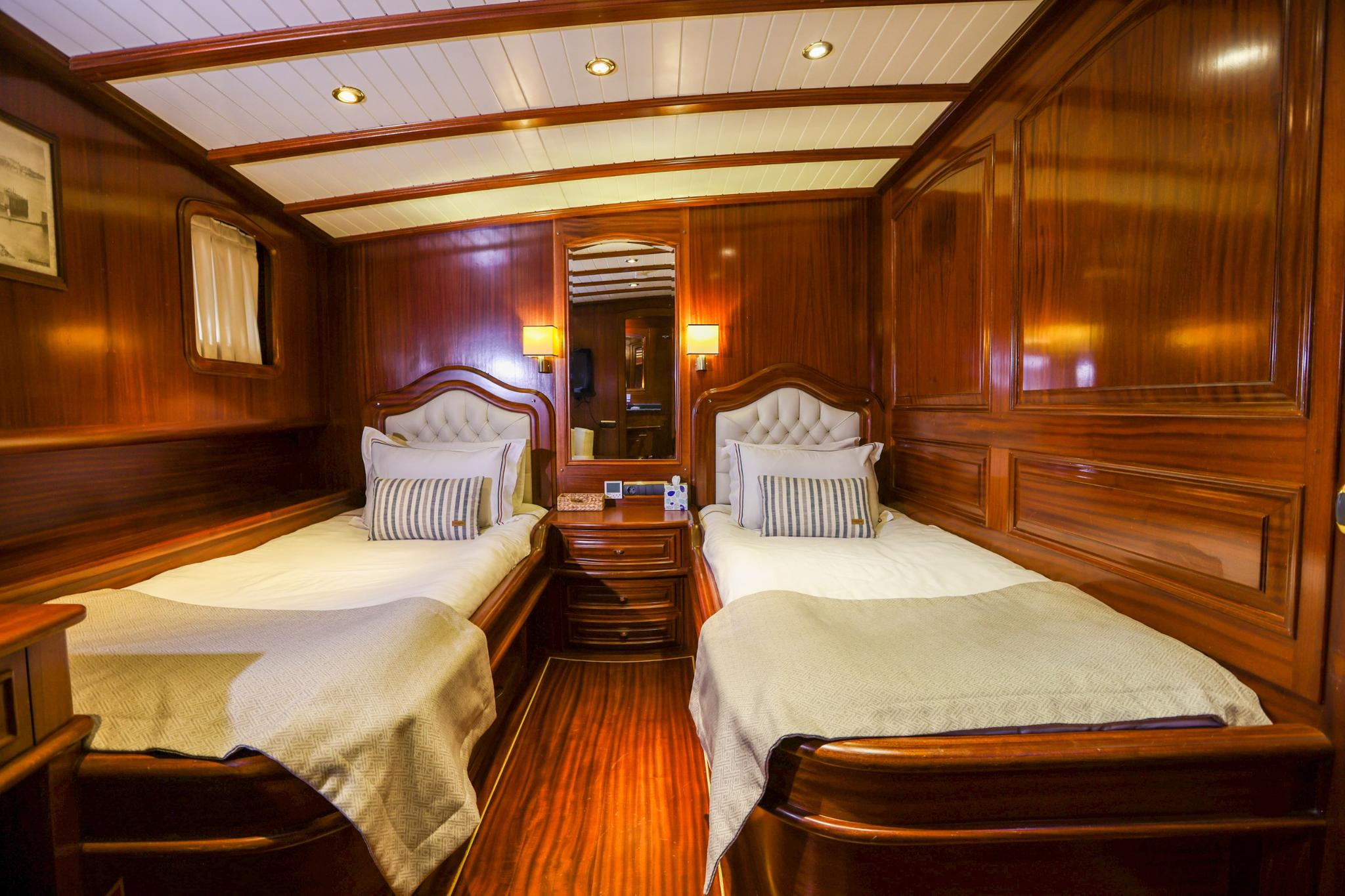 luxury yacht twin bed guest cabin with mahogany paneling and tufted headboards