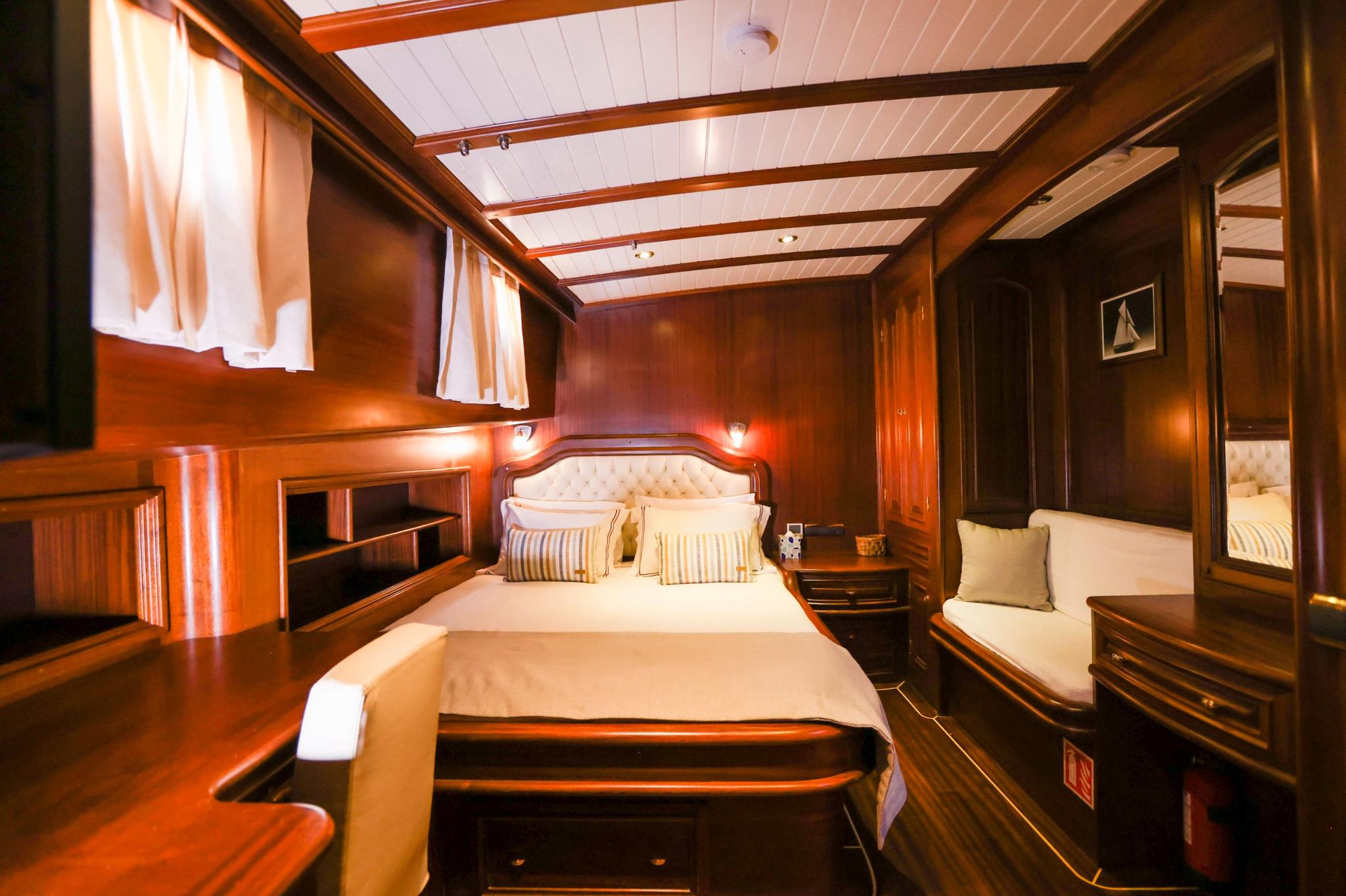 yacht guest cabin featuring double bed with striped pillows, built-in seating, and warm wood paneling