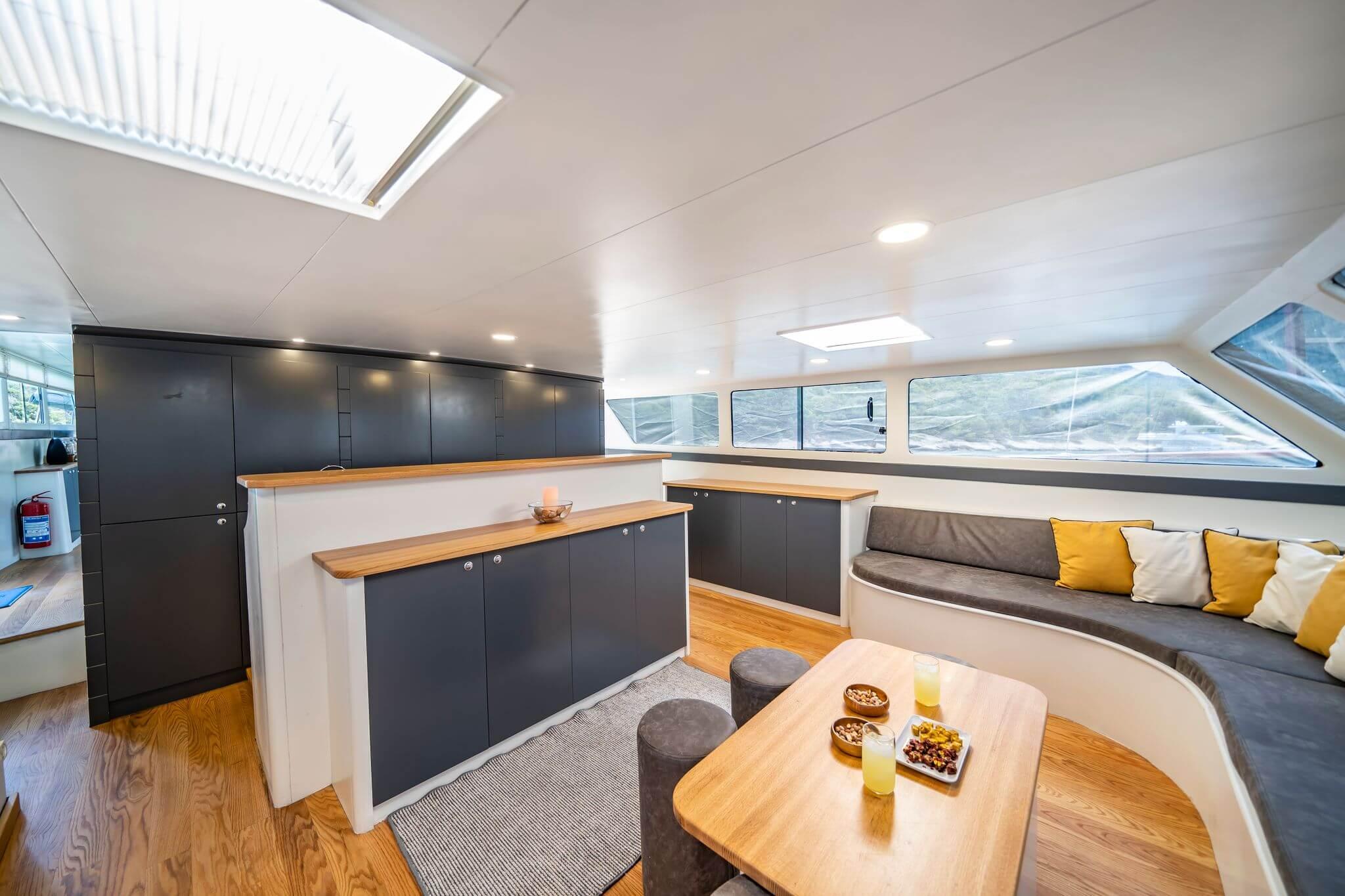 Yacht saloon seating area with wooden coffee table, two glasses of juice, nuts and snacks served on trays