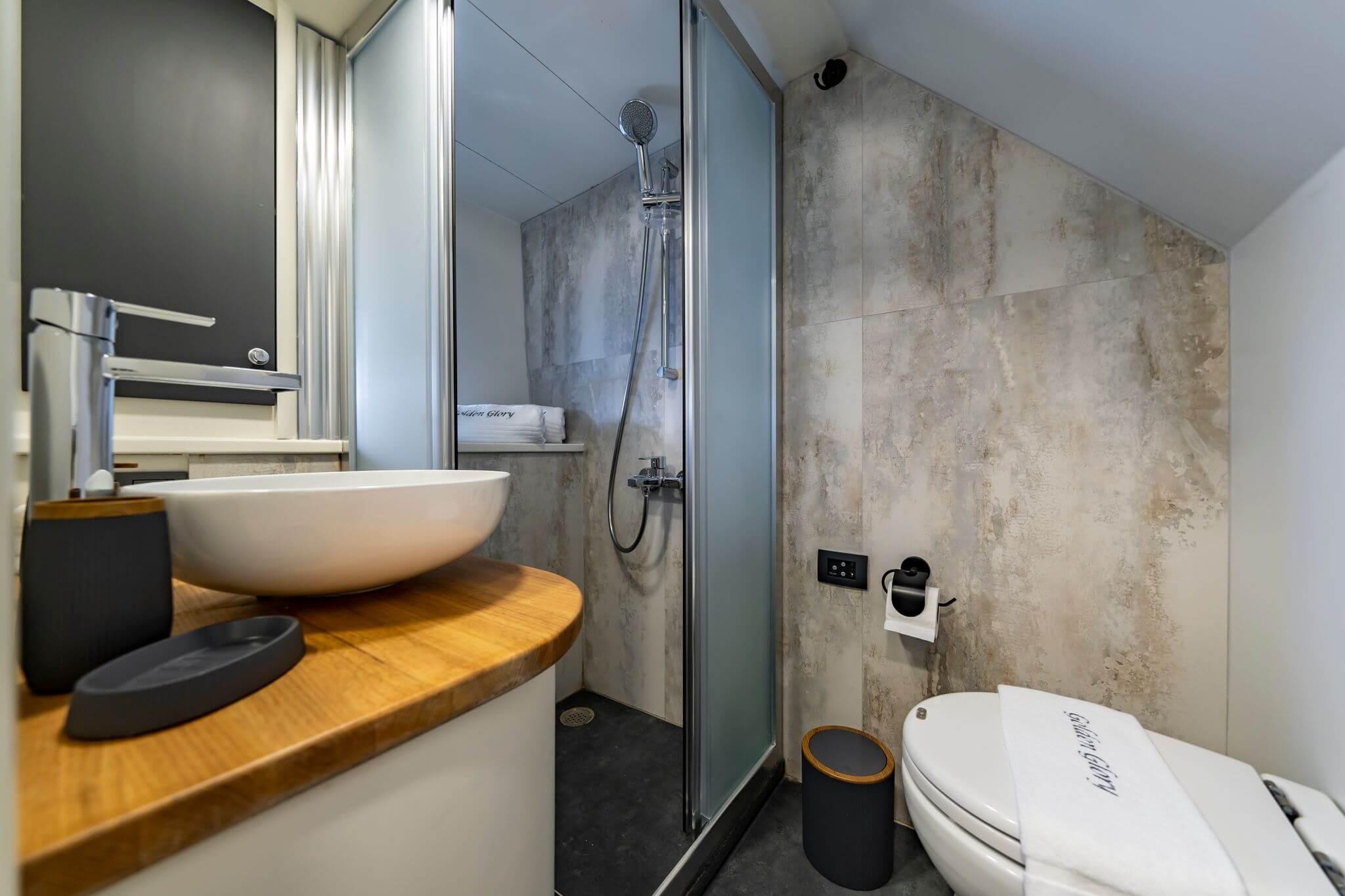 Gulet en-suite bathroom with vessel-basin sink on wood vanity, glass shower cubicle and toilet