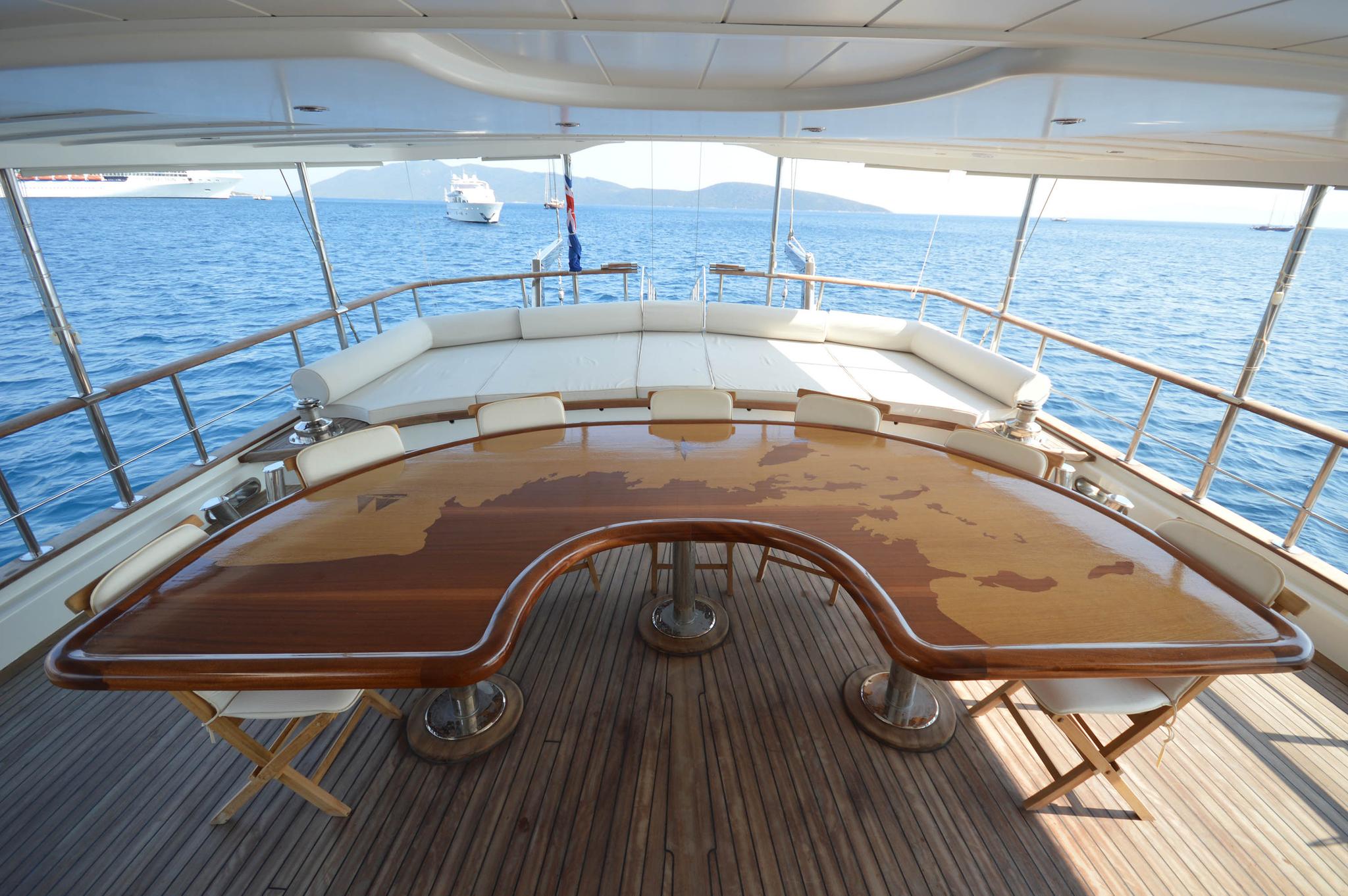 yacht upper deck with curved dining seating and panoramic ocean views