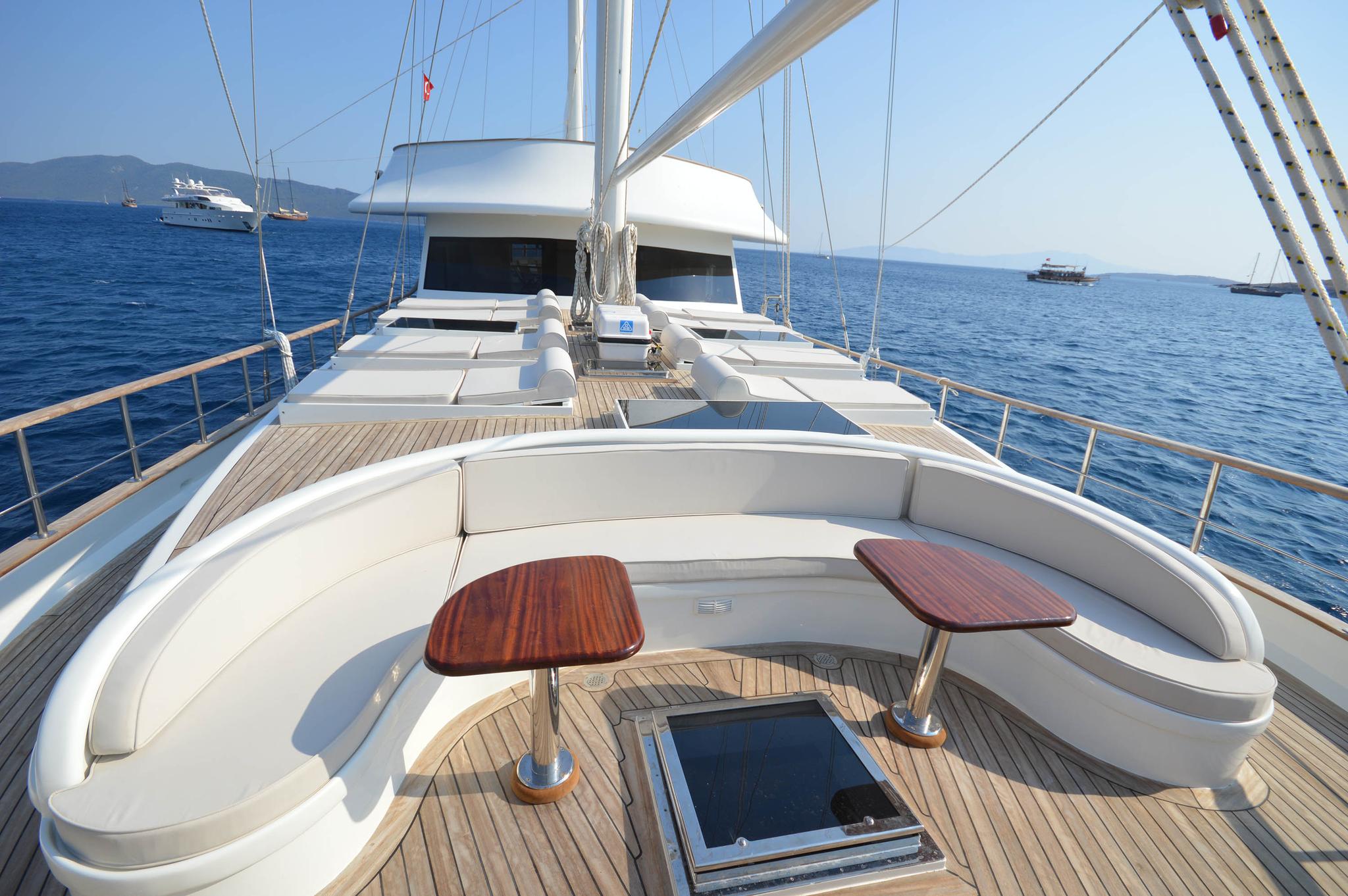 gulet forward deck with curved white seating, teak folding tables and teak decking