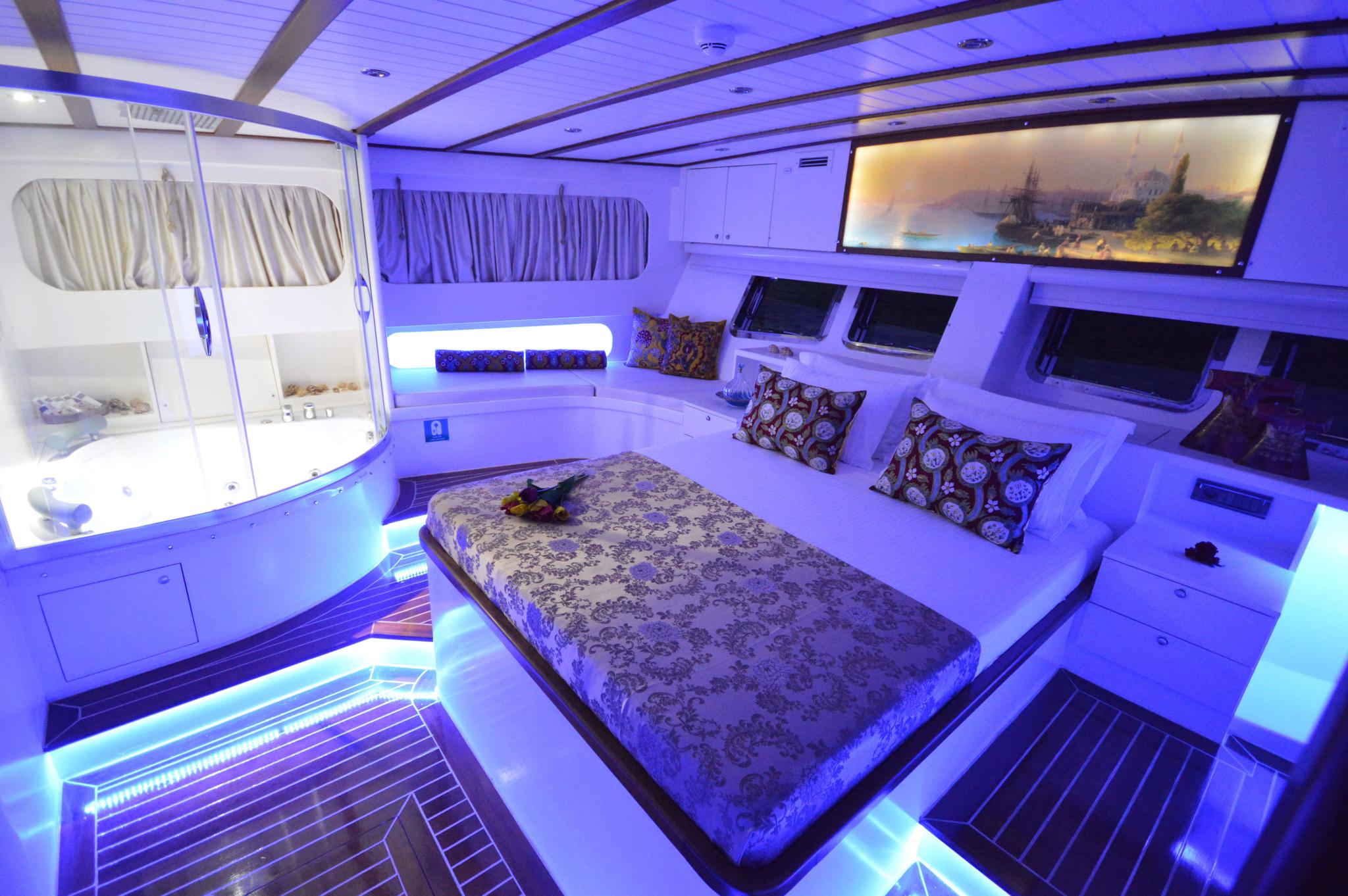 luxury yacht master cabin featuring king bed with patterned bedding and blue LED ambient lighting