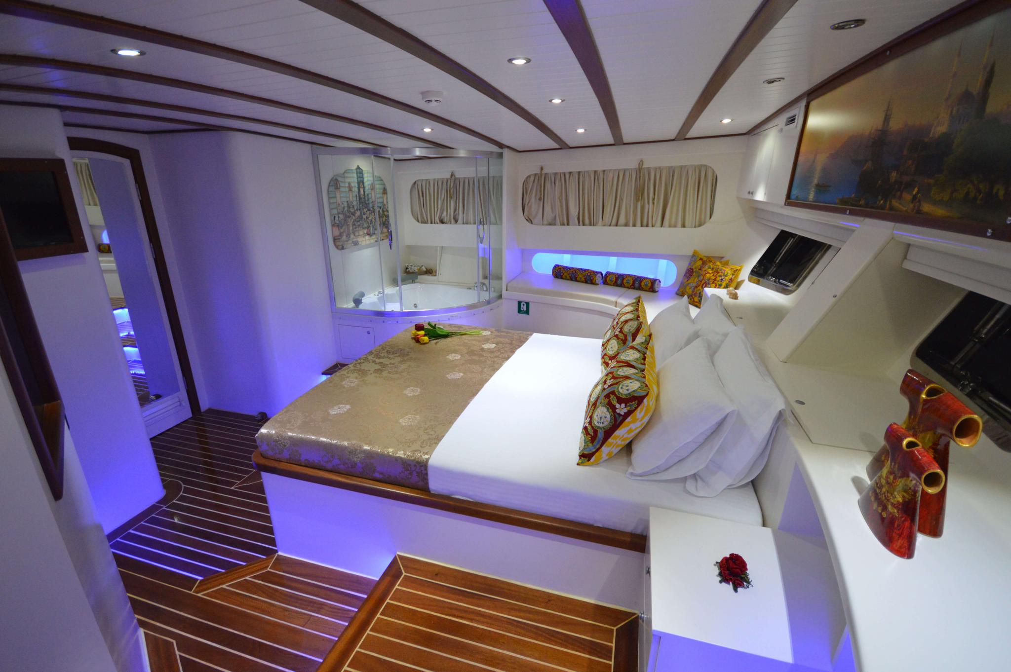 Luxury yacht master cabin featuring double bed, en-suite bathroom with bathtub, and ambient purple lighting
