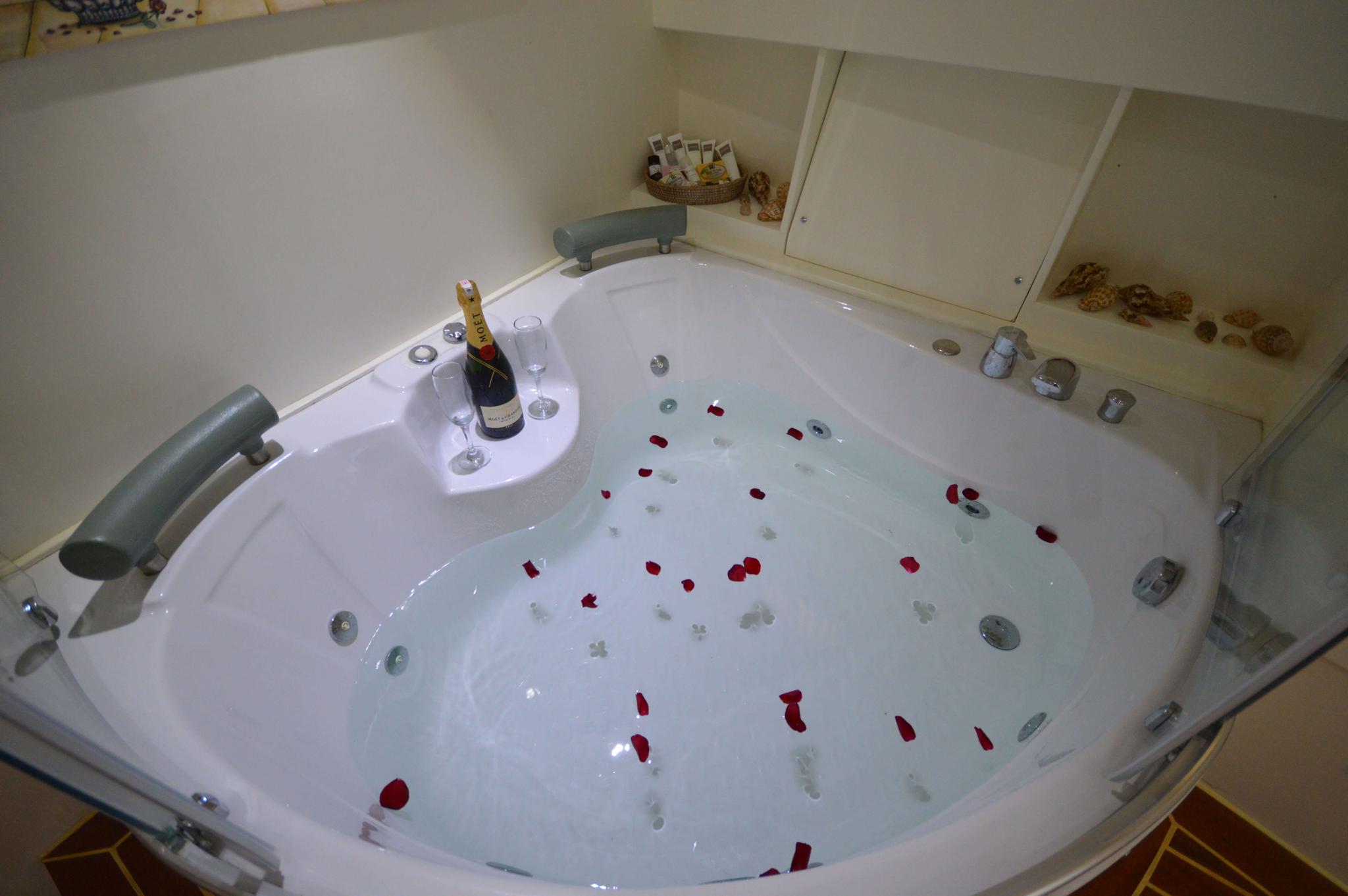 luxury yacht jacuzzi with champagne bottle, glasses and scattered red rose petals