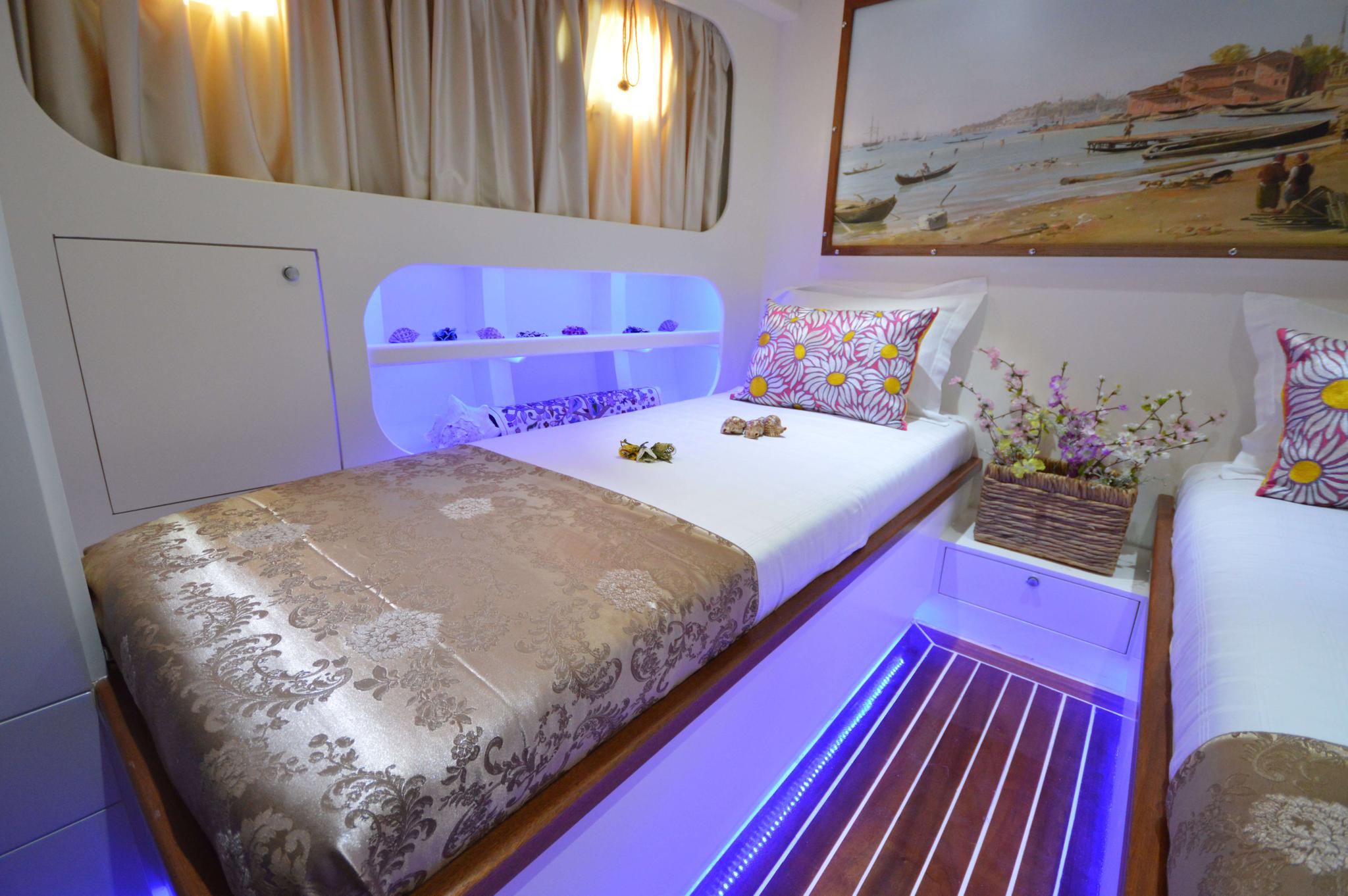 yacht twin cabin with golden bedding and purple LED accent lighting