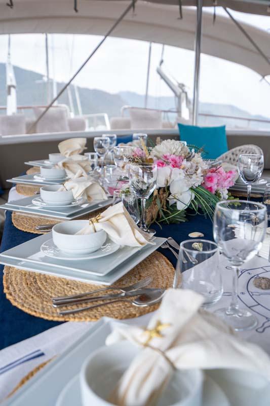 elegant yacht dining table with white plates, crystal glasses, floral centerpiece and beige napkins