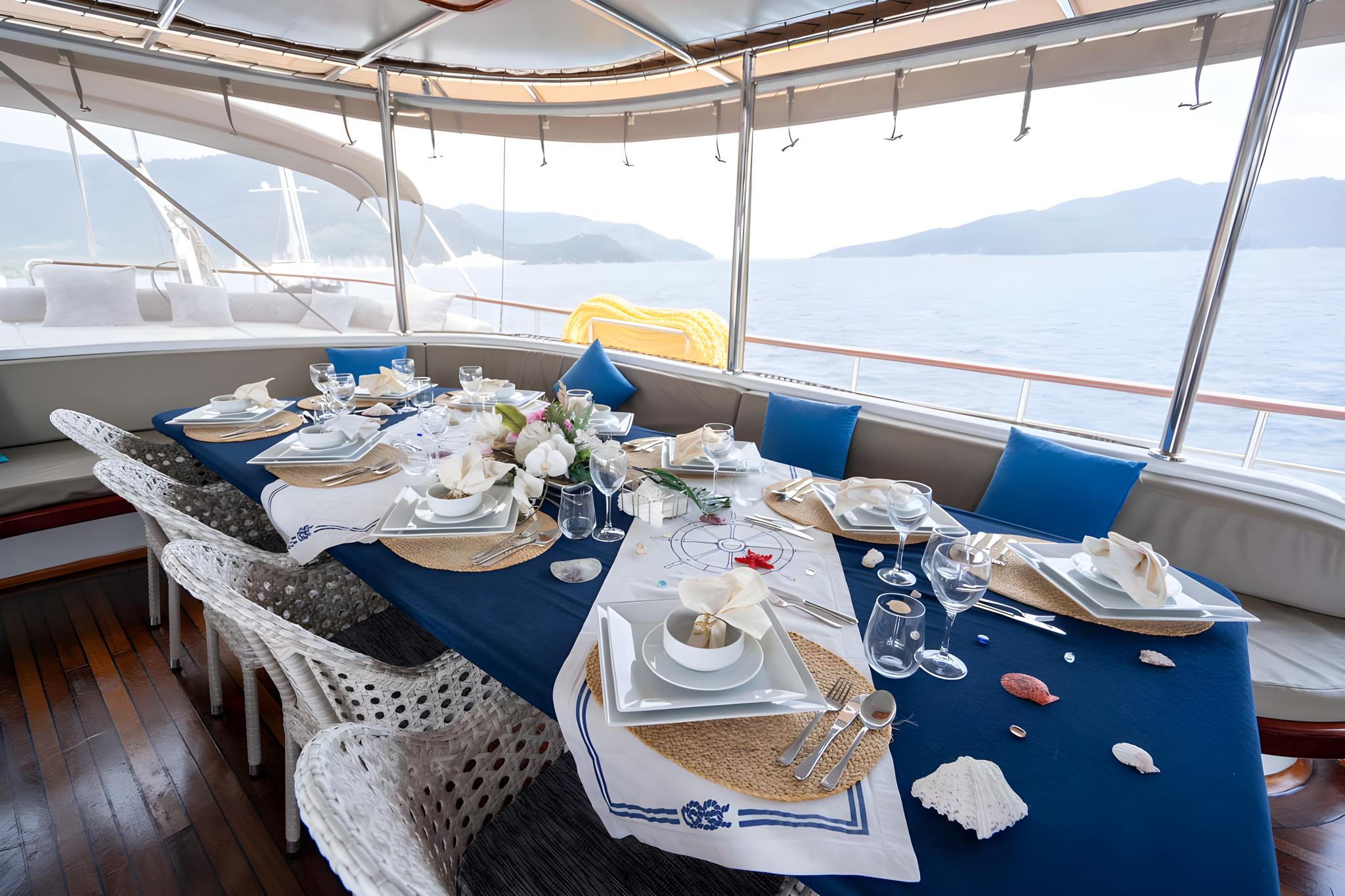 elegant yacht dining table with blue runner, white plates, wine glasses and nautical napkins