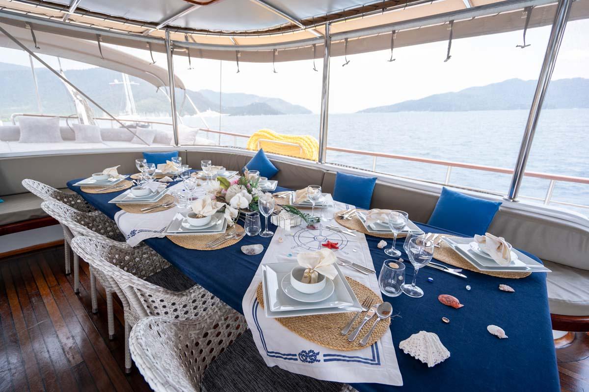 elegant yacht dining table with blue runner, white plates, wine glasses and nautical napkins