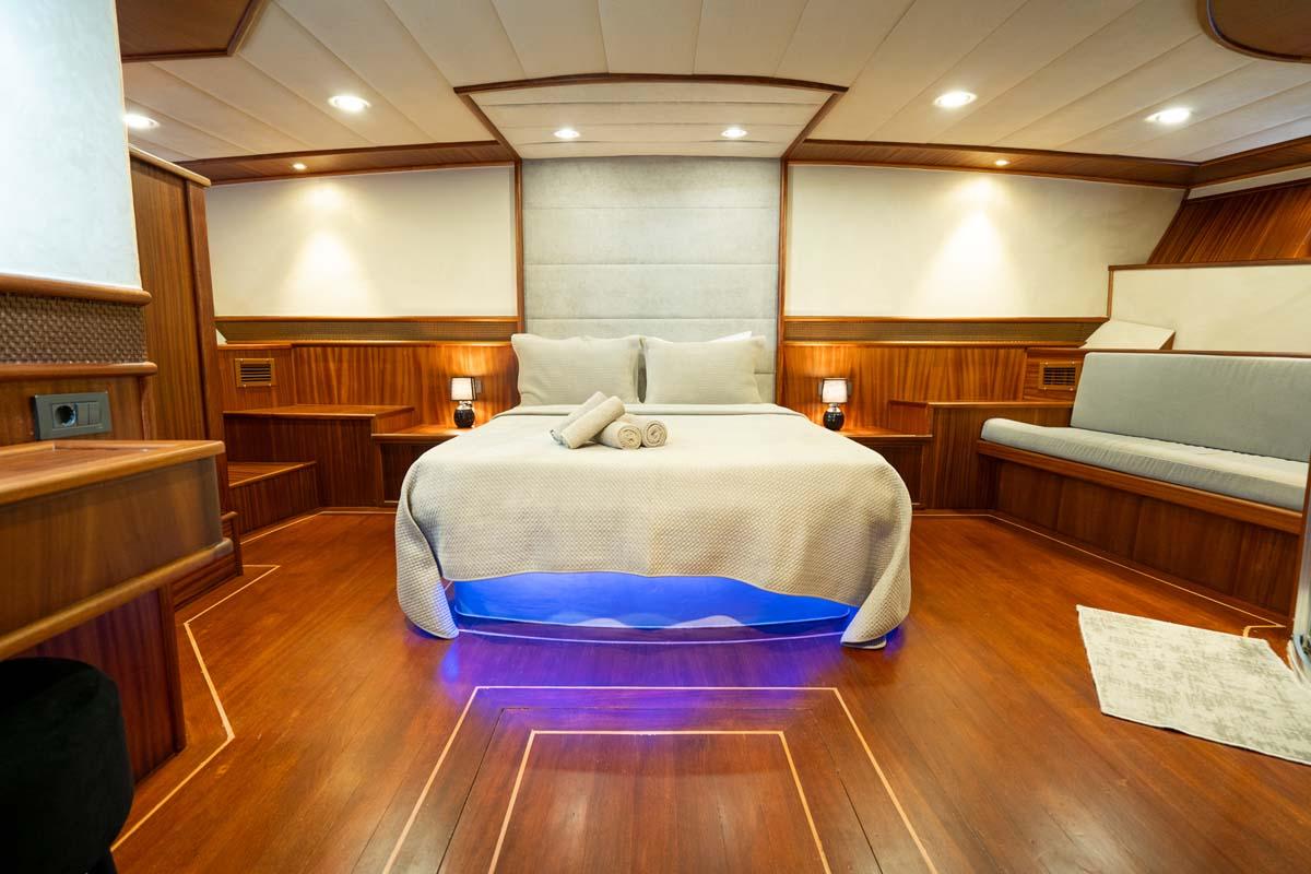 Luxury yacht master cabin with double bed, cream upholstered headboard, and blue LED accent lighting