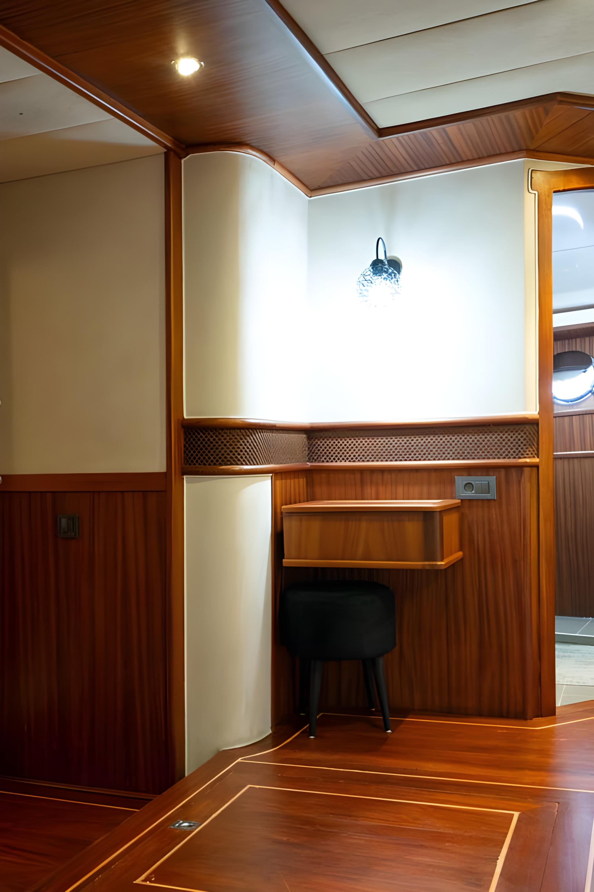 yacht cabin interior featuring built-in wooden desk with chair and cream upholstered seating