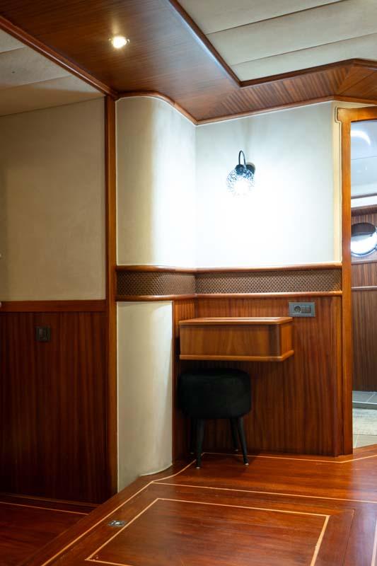 yacht cabin interior featuring built-in wooden desk with chair and cream upholstered seating