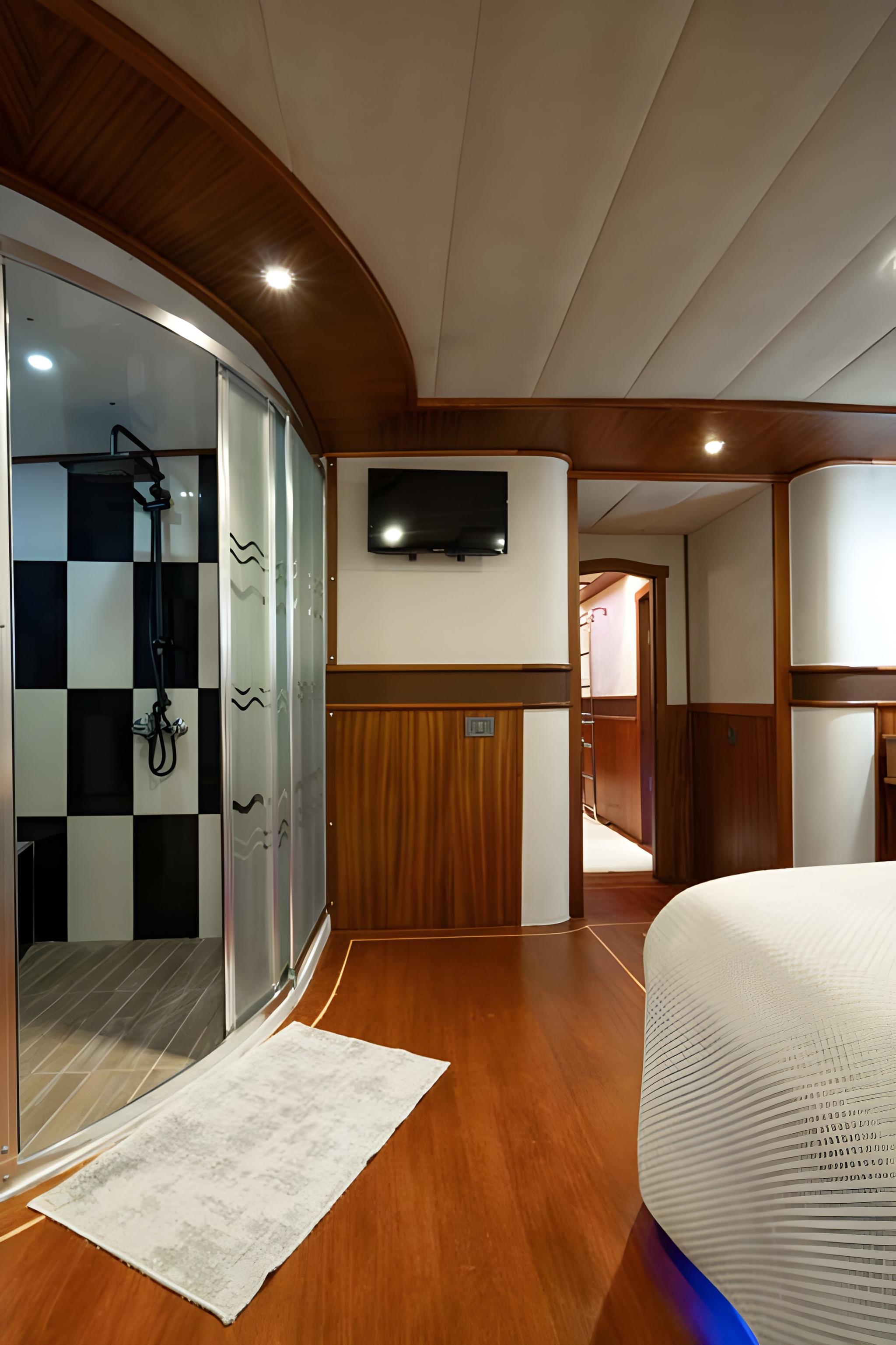 yacht cabin interior featuring glass-enclosed shower with checkered tiles and wall-mounted TV