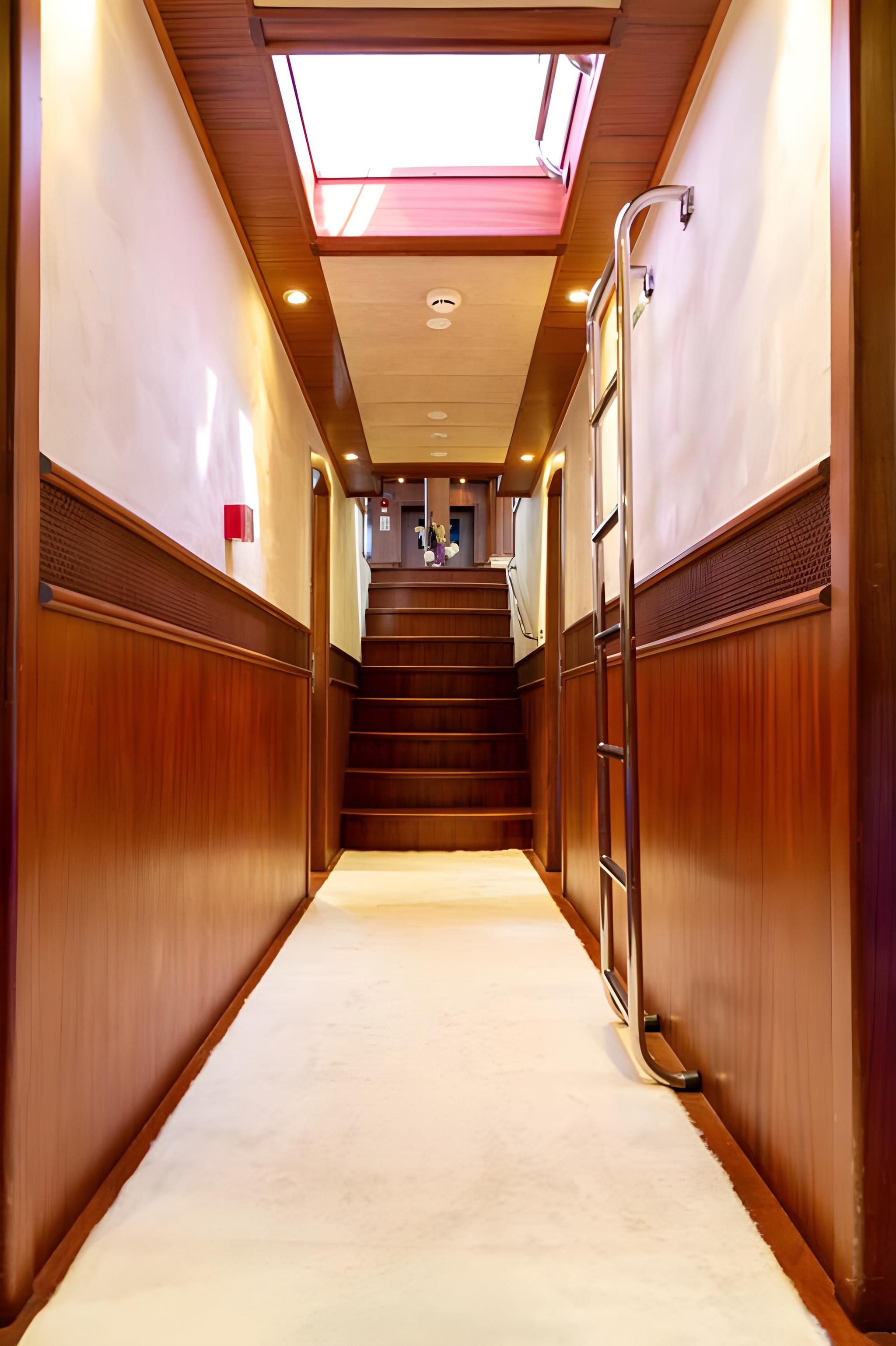 yacht interior corridor with wooden paneling, stairs, and overhead skylight