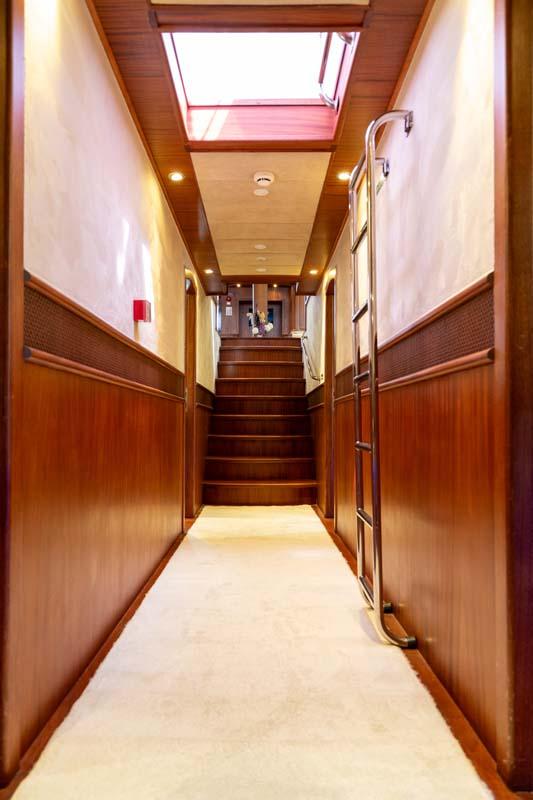 yacht interior corridor with wooden paneling, stairs, and overhead skylight