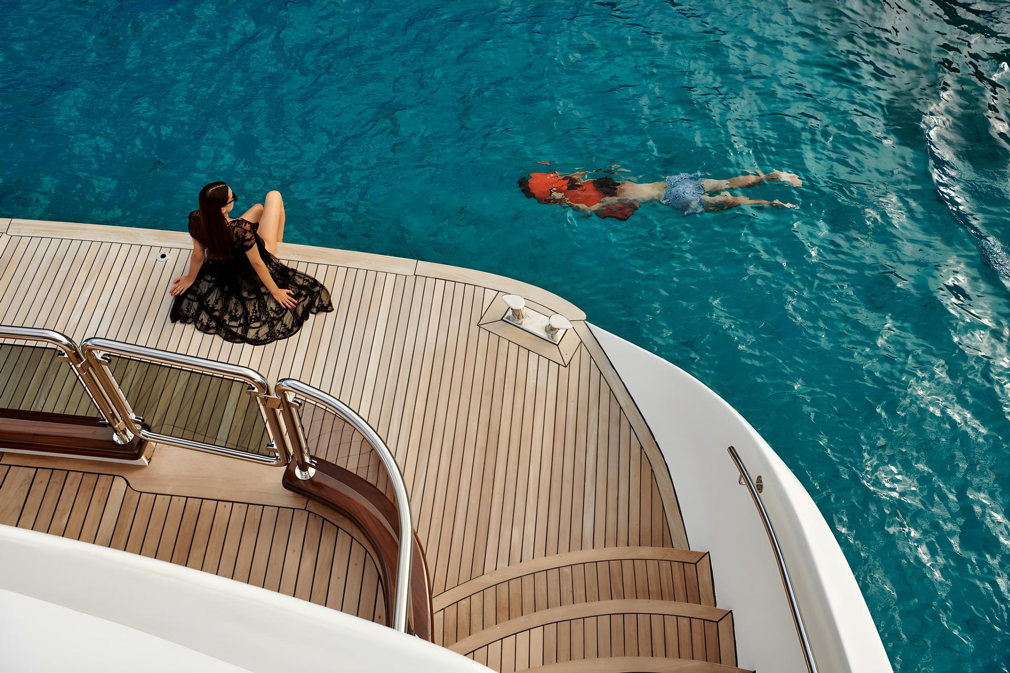 luxury yacht curved teak swim platform with steel ladder and clear turquoise water