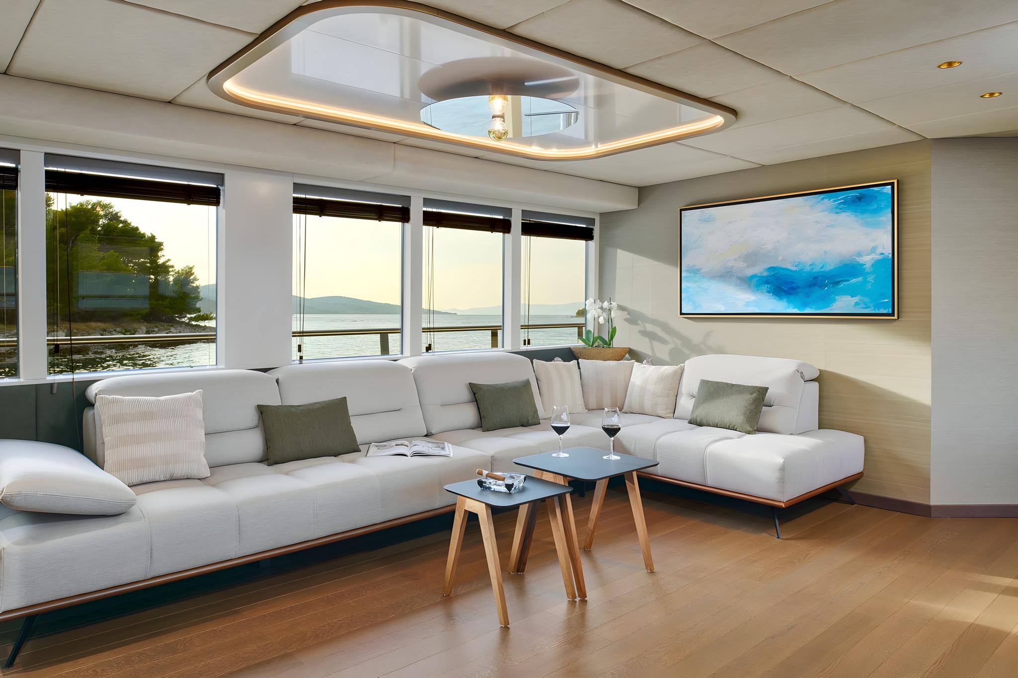 Luxury yacht main salon featuring gray sectional sofa and panoramic windows