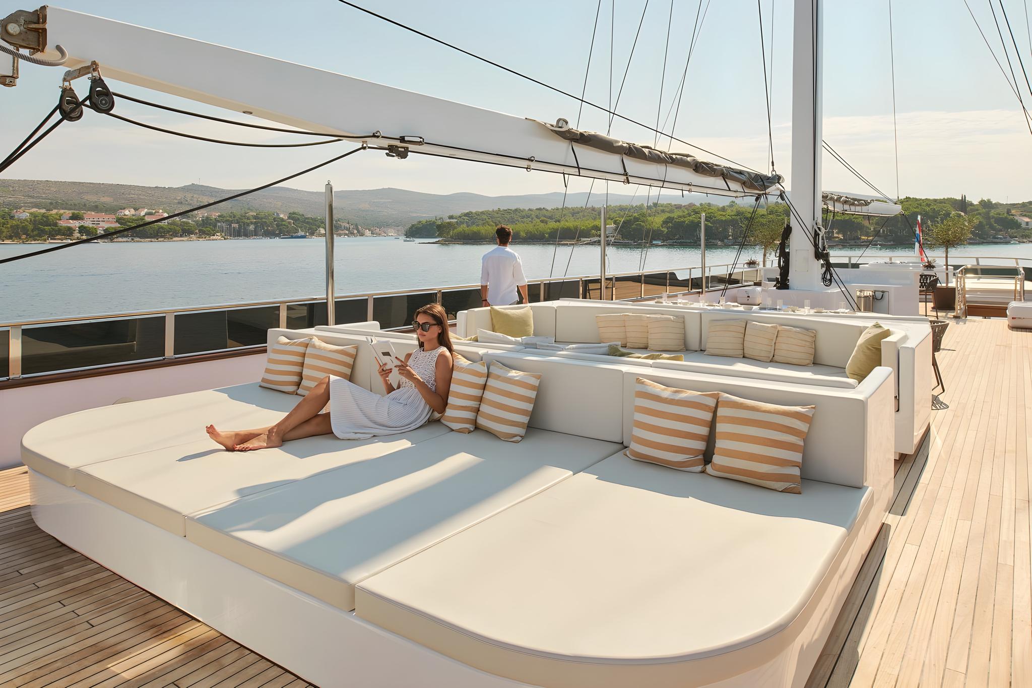 luxury sailing yacht main deck with white sunbed and guest lounging
