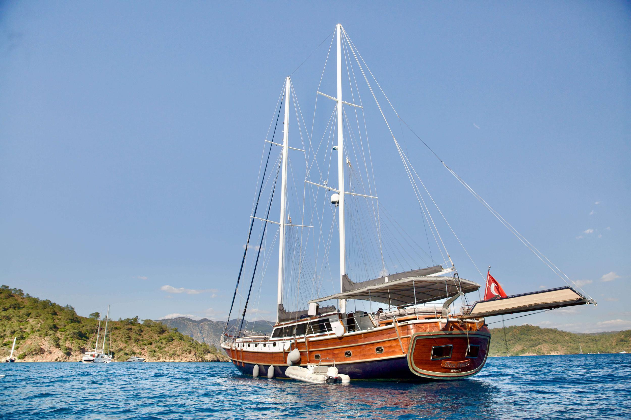 Traditional wooden gulet yacht with two white masts anchored in blue Mediterranean waters