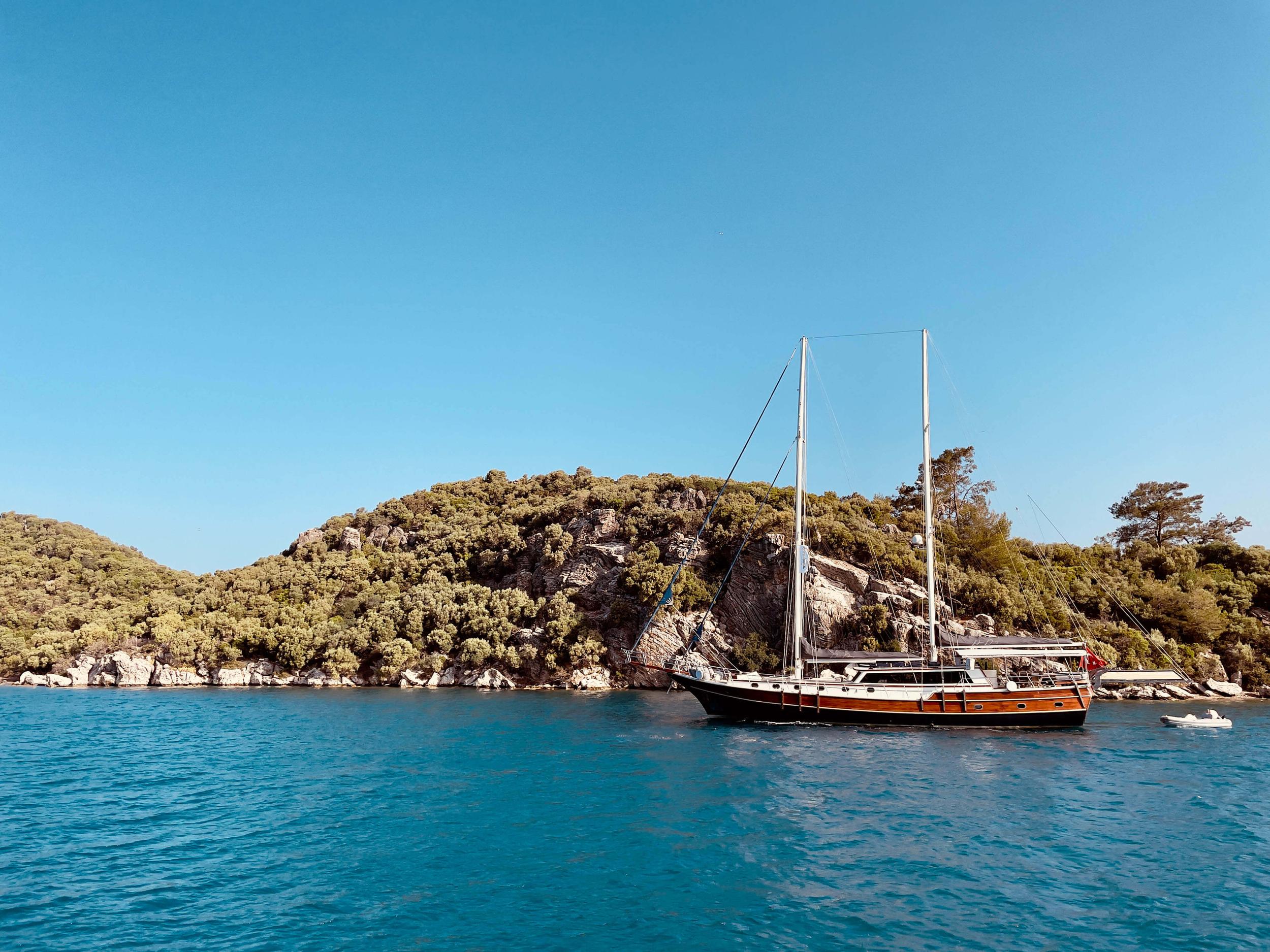 traditional wooden gulet yacht anchored in crystal clear turquoise waters near Mediterranean coastline