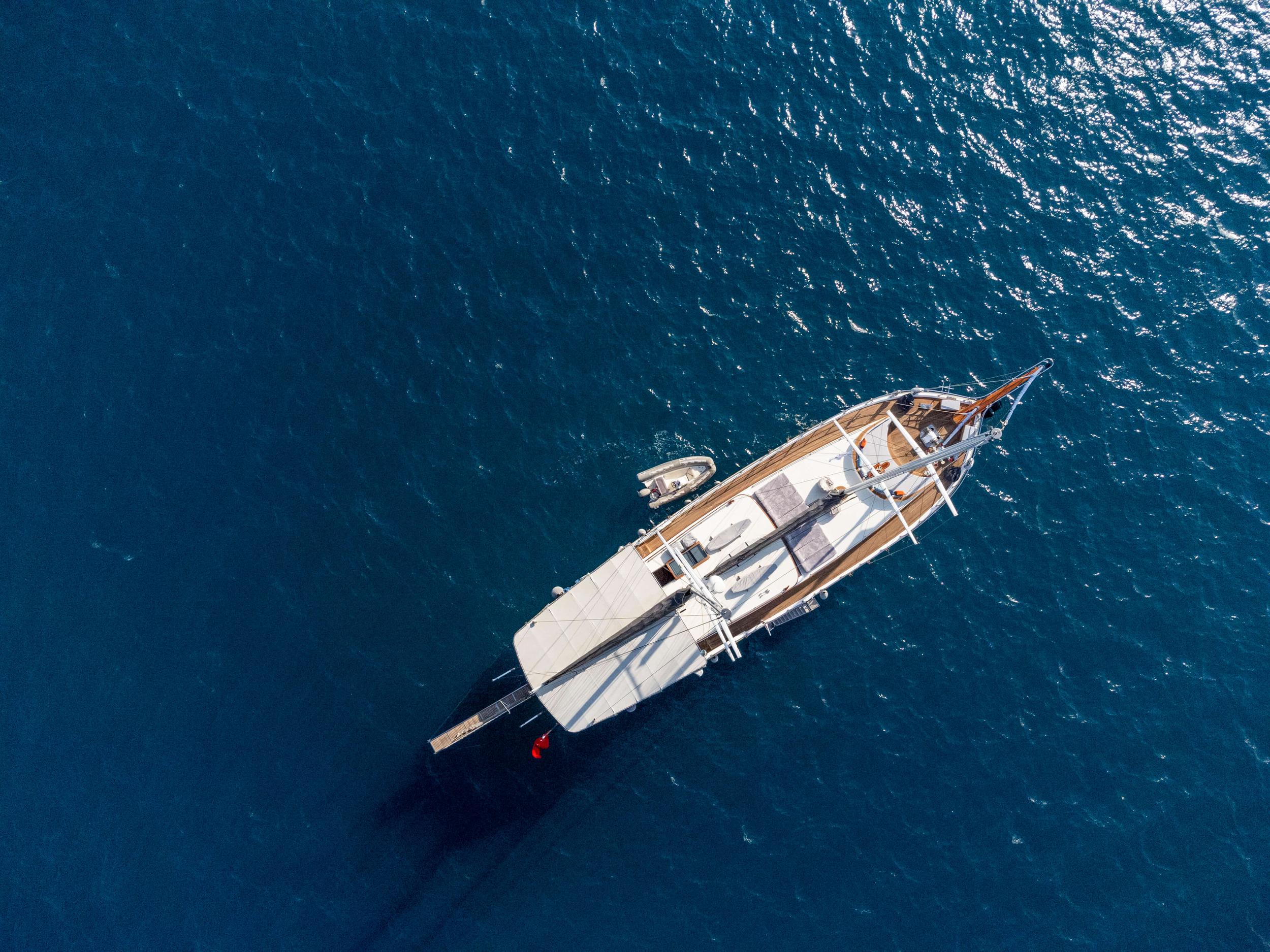 overhead aerial view of white luxury gulet yacht anchored in deep blue Mediterranean waters