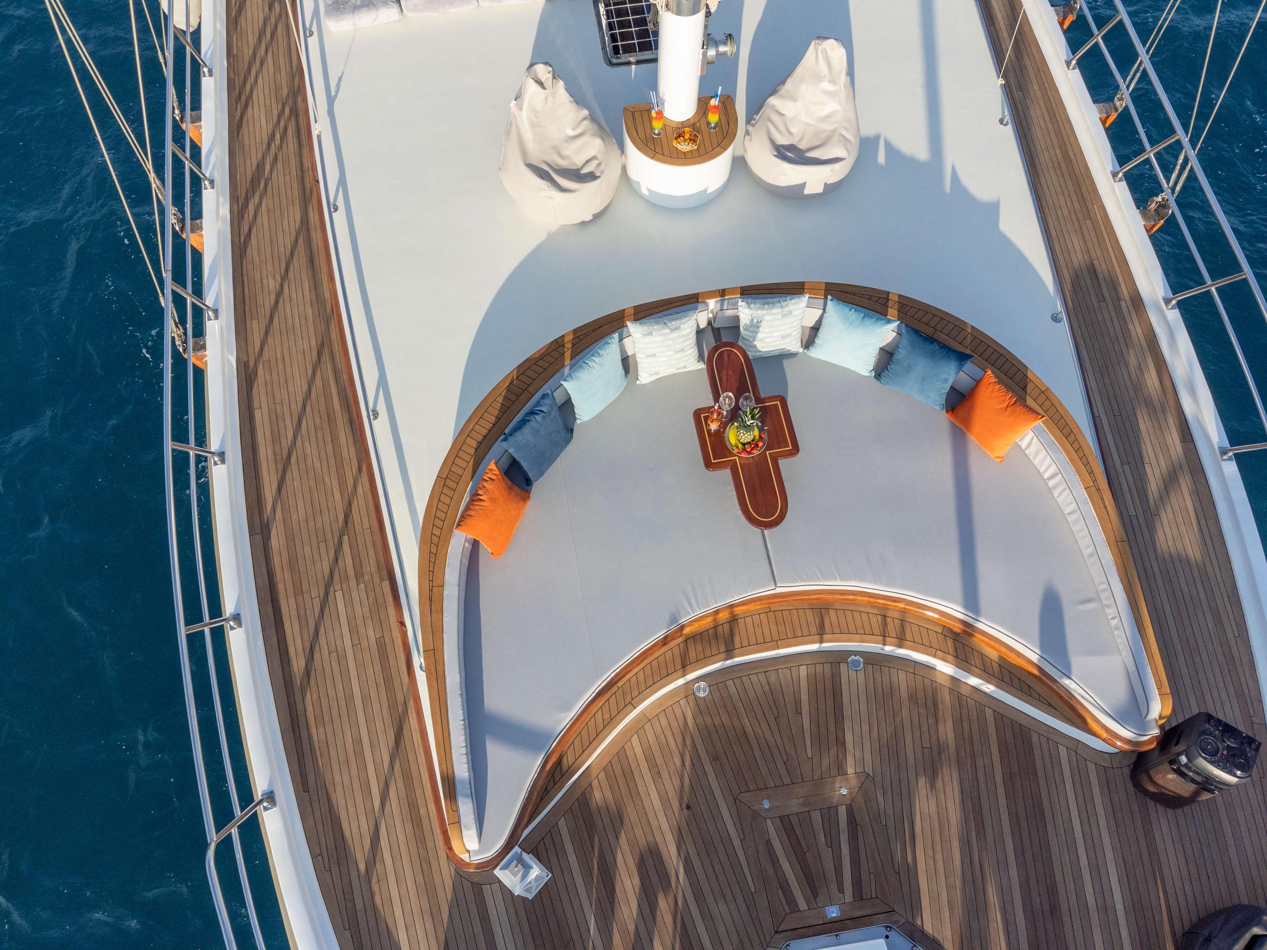 luxury yacht curved bow seating area with white cushioned banquette and wooden coffee table