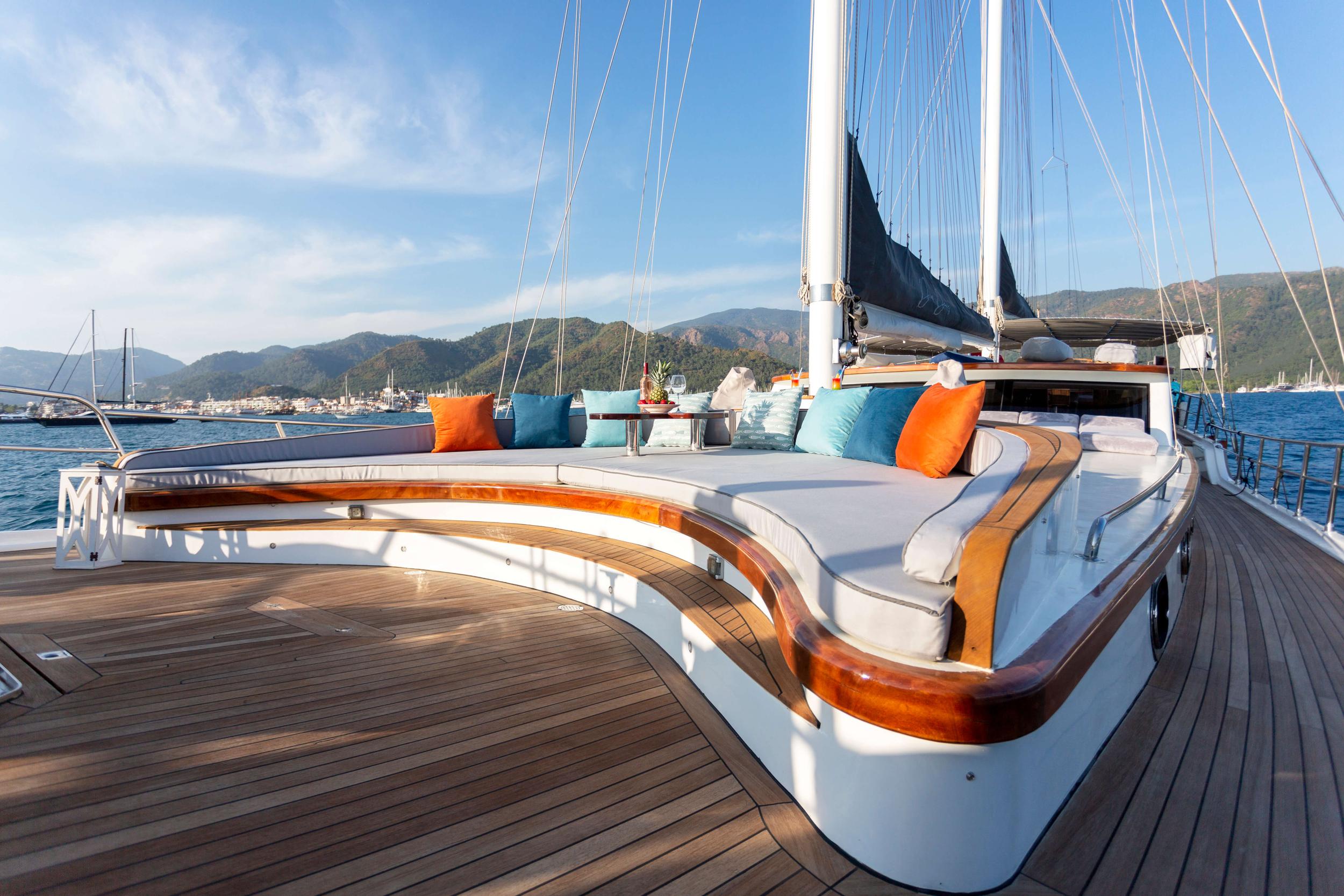 gulet forward deck with curved white seating, colorful cushions and sail rigging
