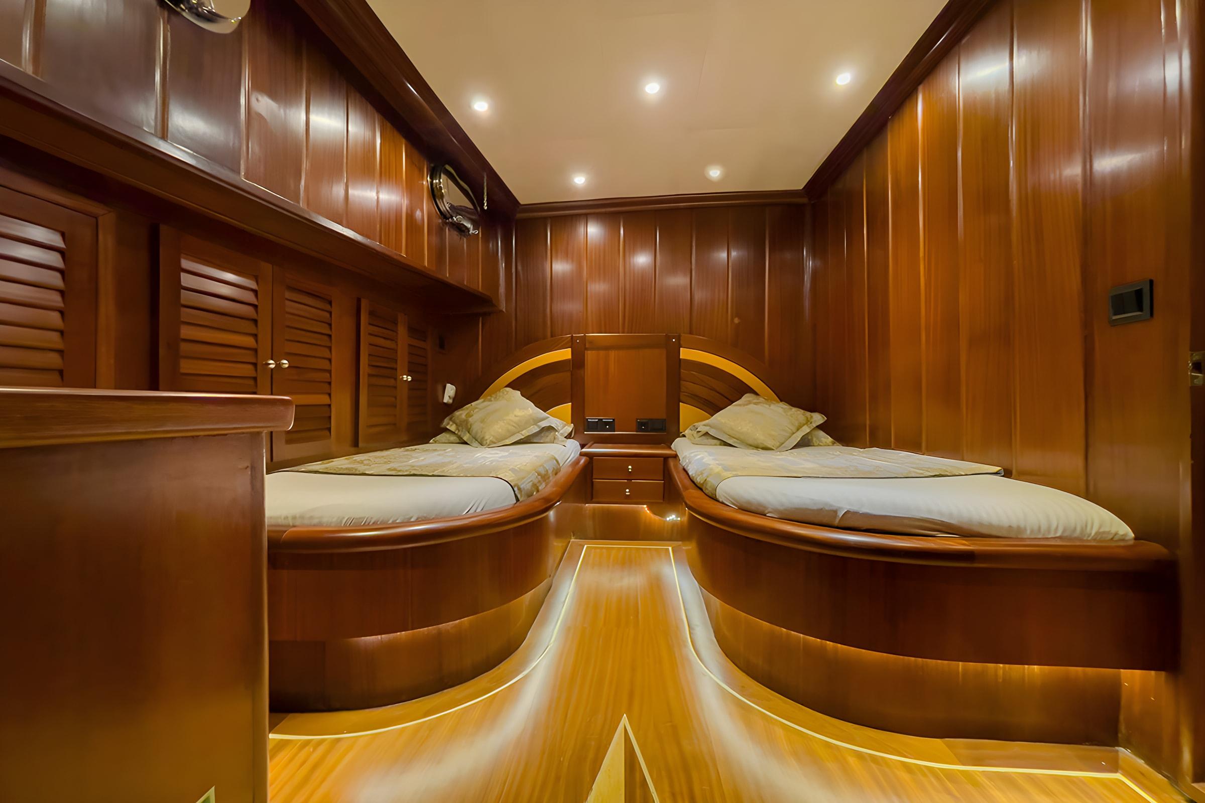 yacht guest cabin featuring twin beds with curved headboards and rich wood paneling throughout